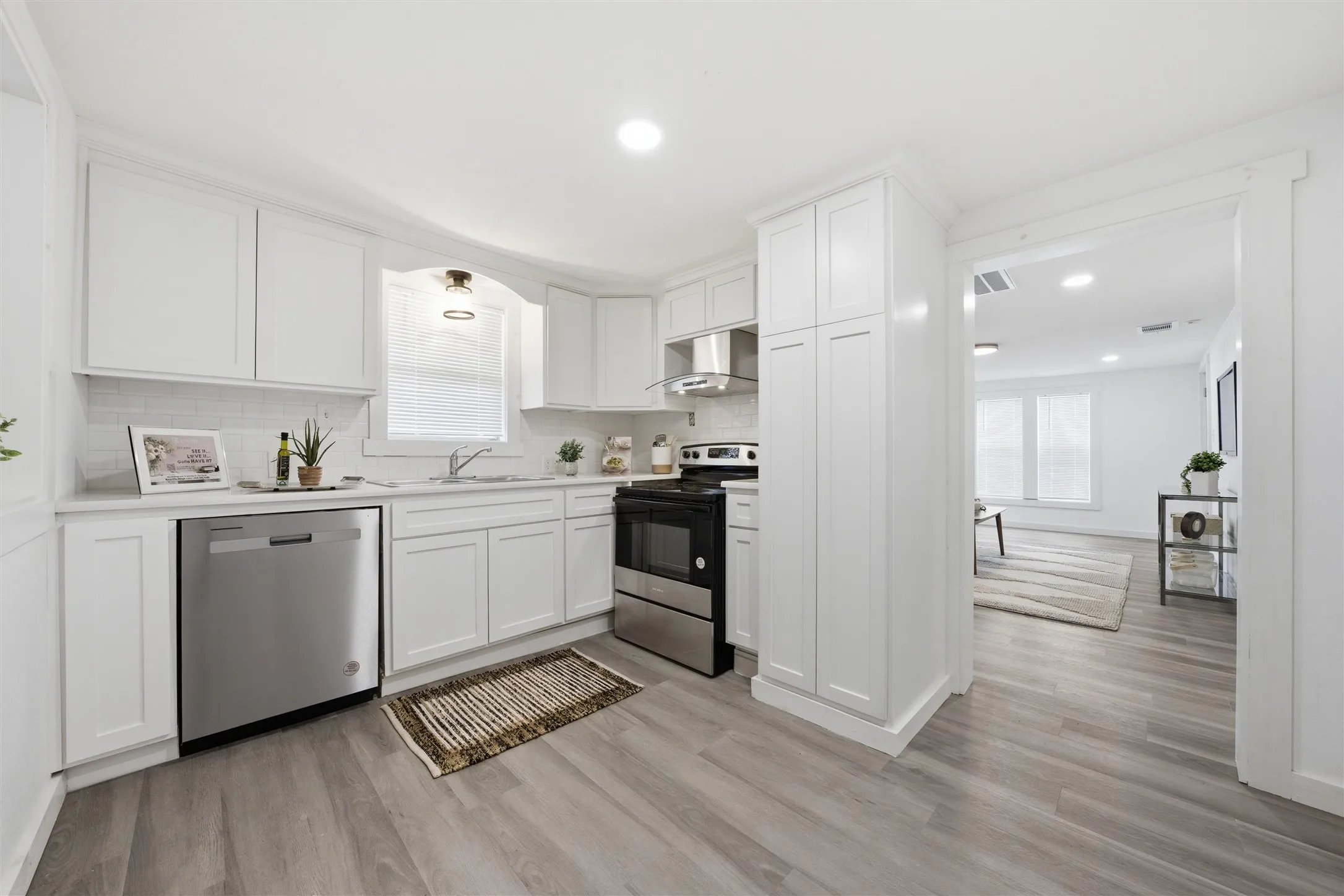 Kitchen with stainless steel appliances, white cabinets, light countertops, light wood finished floors, and recessed lighting