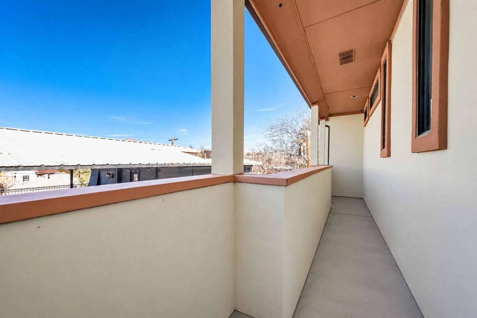 Covered balcony with a solid railing, concrete flooring, and recessed ceiling lighting