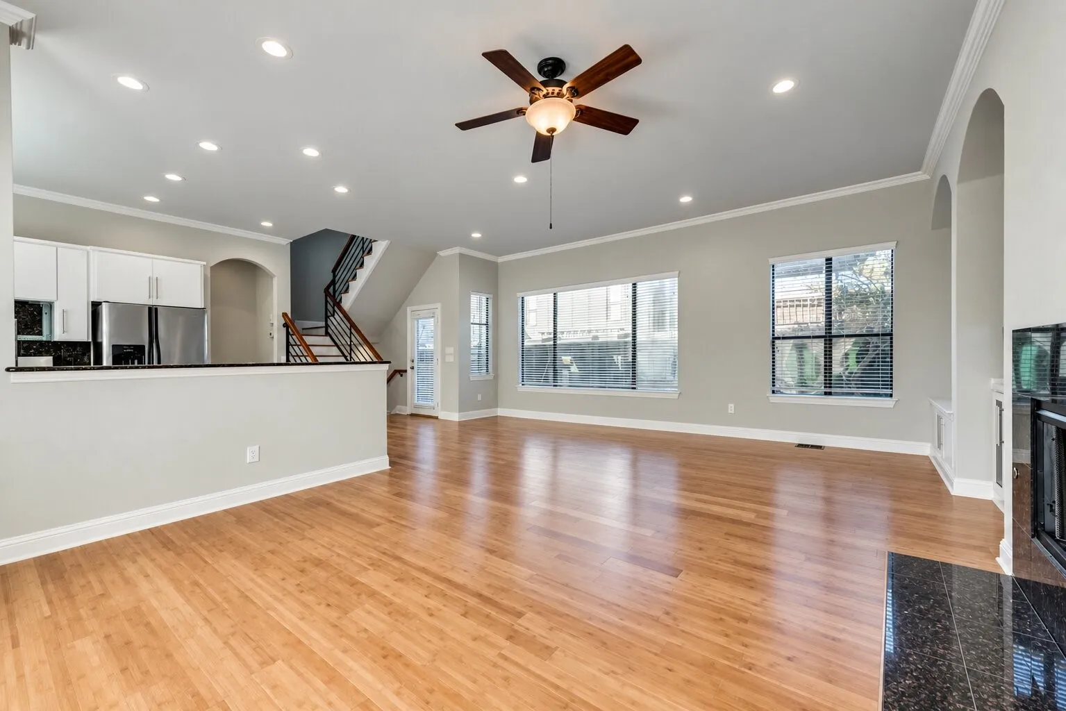 Expansive living area with wood-finish flooring, recessed lighting, and a ceiling fan