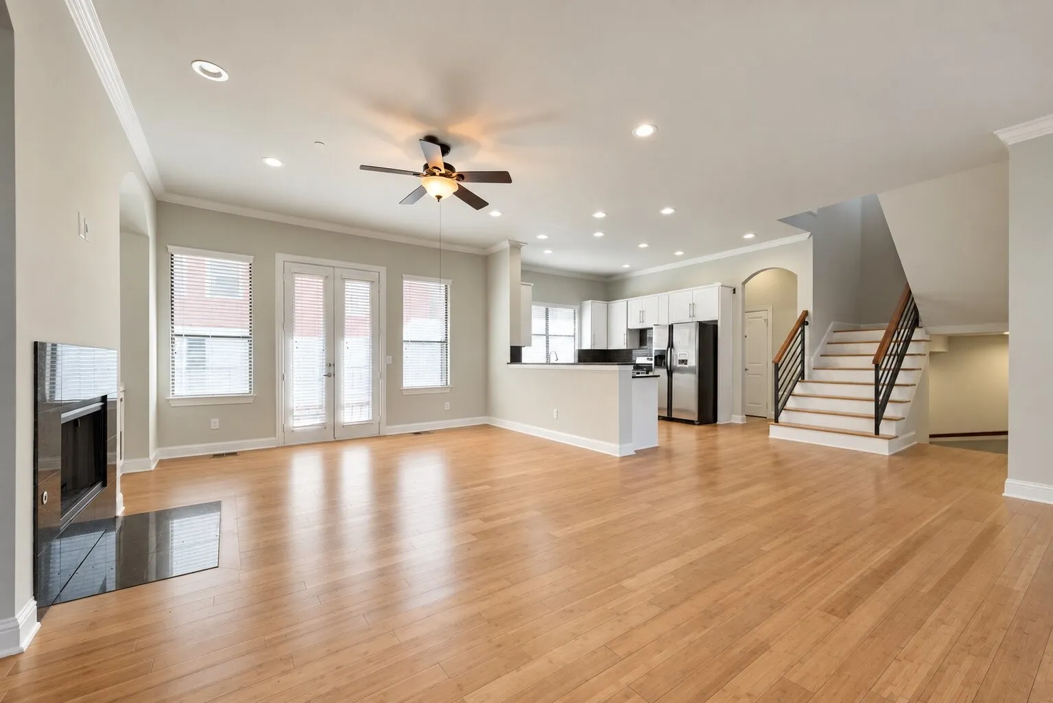 Light wood-finish flooring throughout, recessed lighting, and a modern fireplace with a black surround