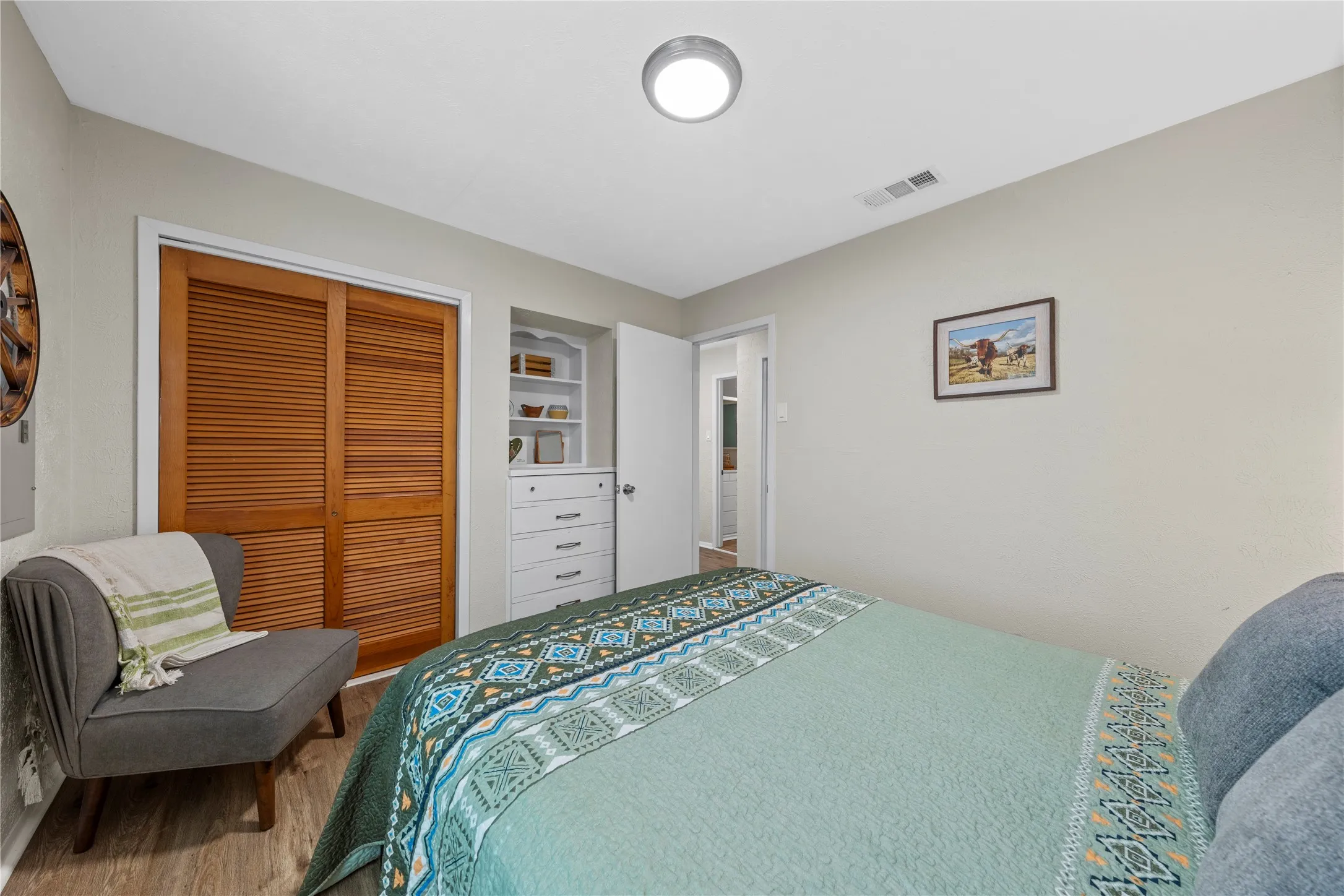 Bedroom with wood finished floors and a closet