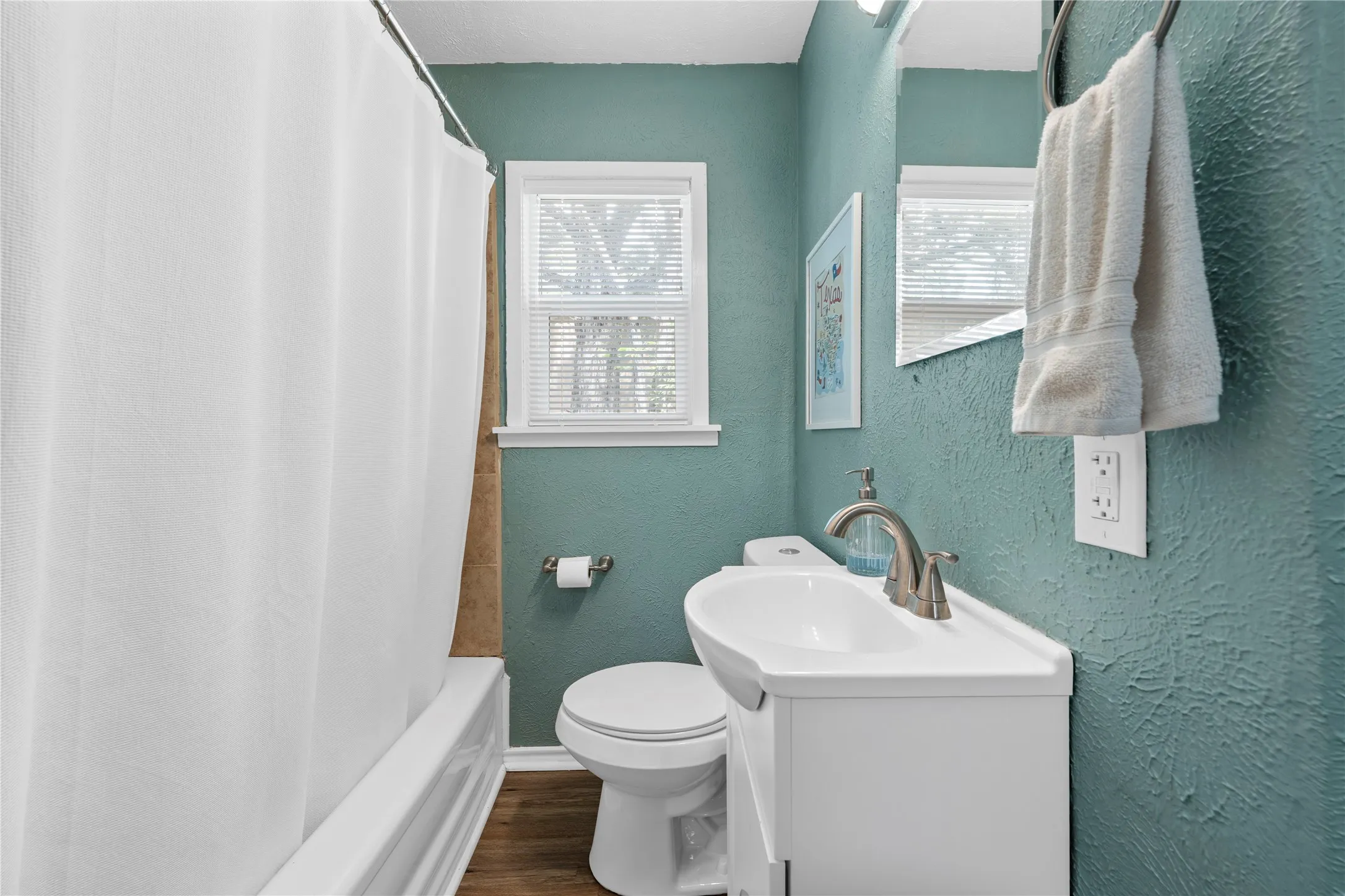 Full bathroom with a textured wall, vanity, shower / tub combo, and dark wood-style floors