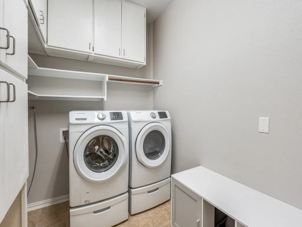 The laundry room features ample storage space, utilizing the tall ceilings with both shelving and cabinetry.