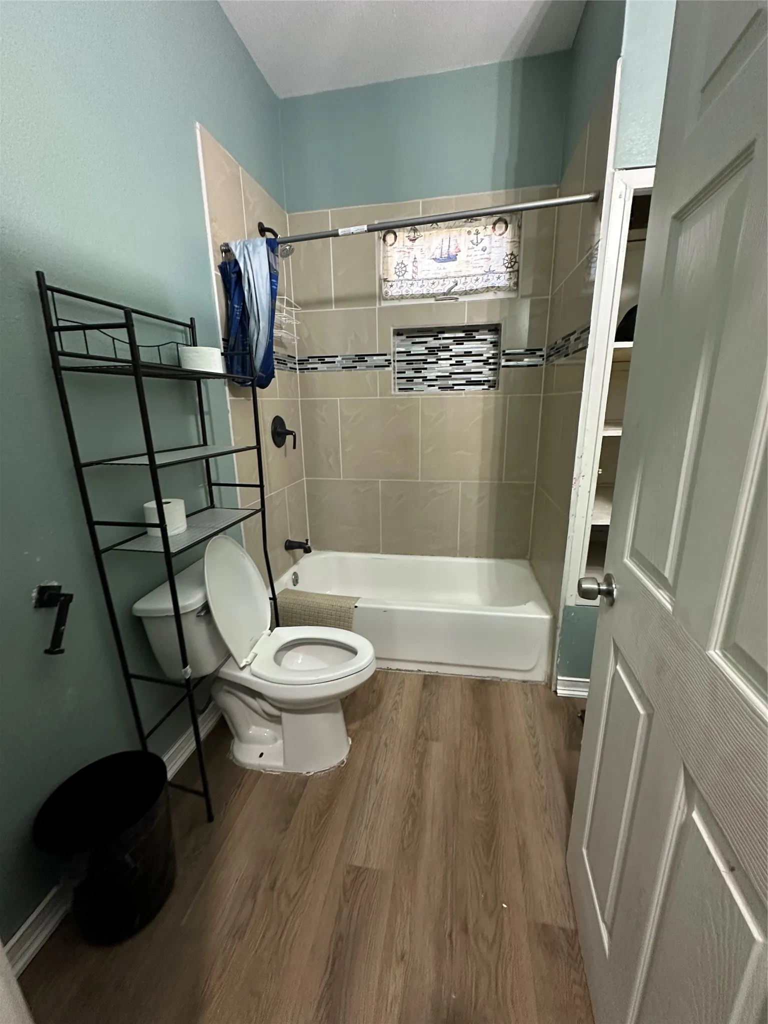 Bathroom with dark wood-style floors and bathing tub / shower combination