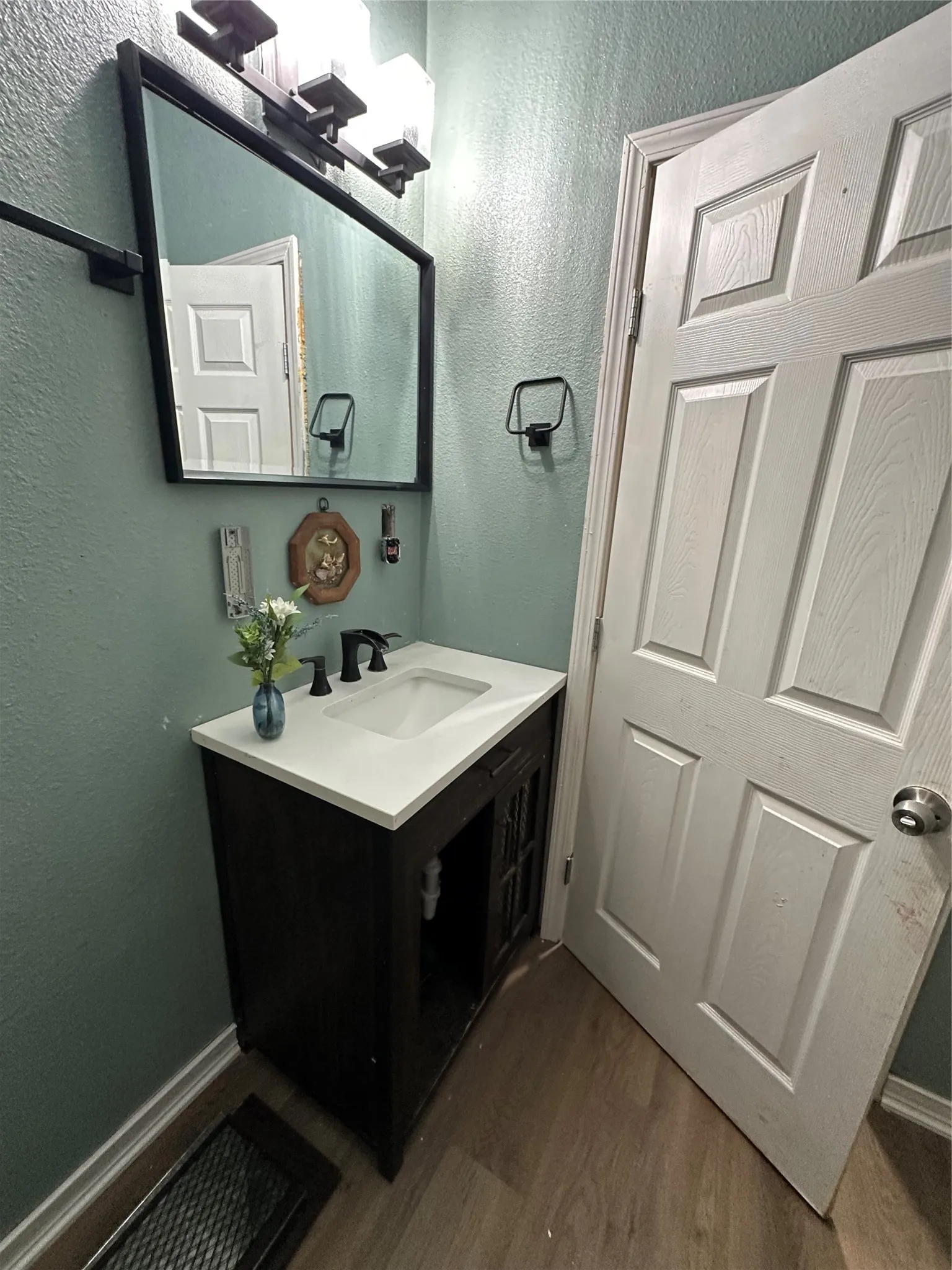 Bathroom featuring a textured wall, dark wood-style flooring, and vanity
