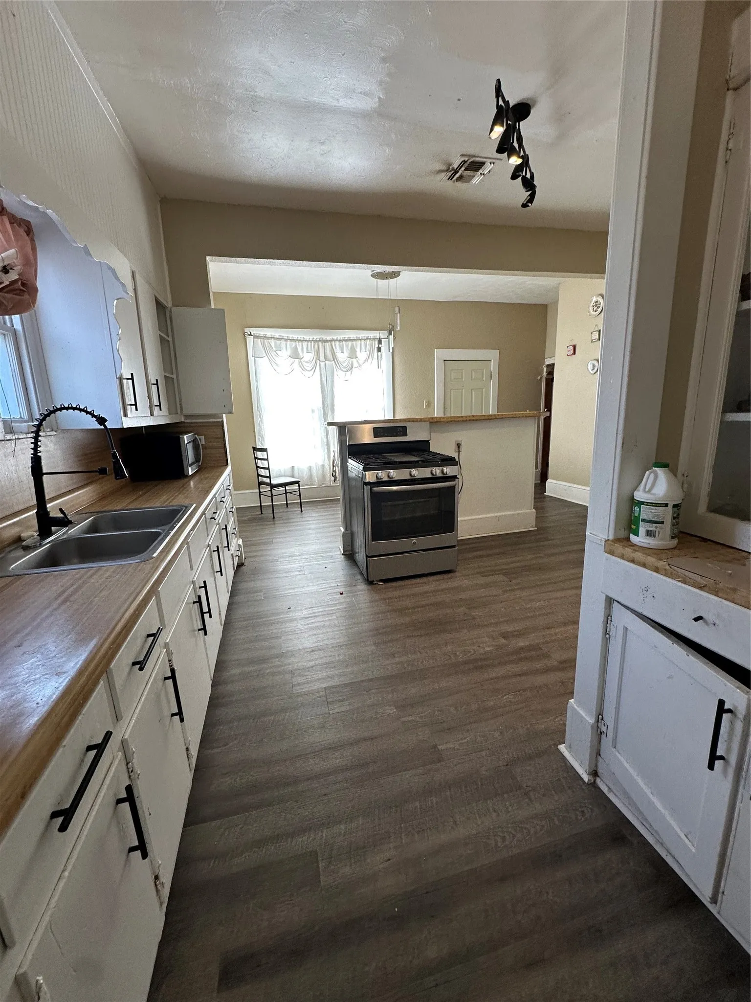 Kitchen with white cabinetry, stainless steel appliances, and dark wood-style floors