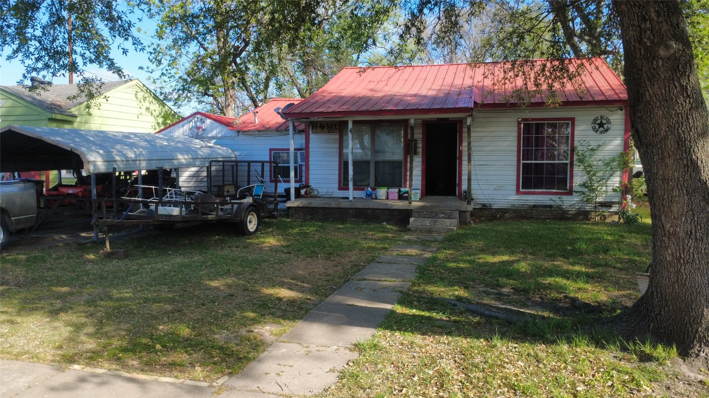 Bungalow-style house featuring a front lawn, a detached carport, oil tank, and a metal roof
