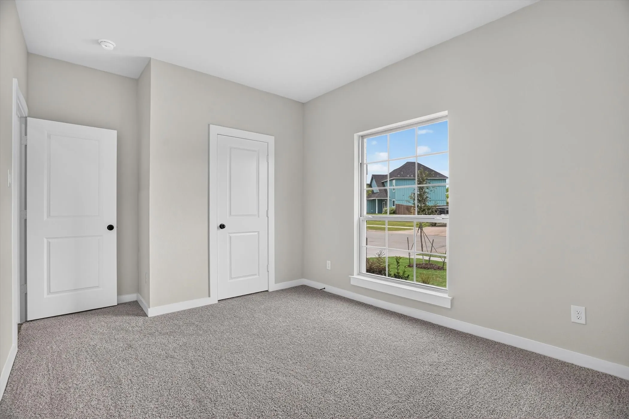 Neutral-toned walls, grey carpeting, white trim, and a white-framed window