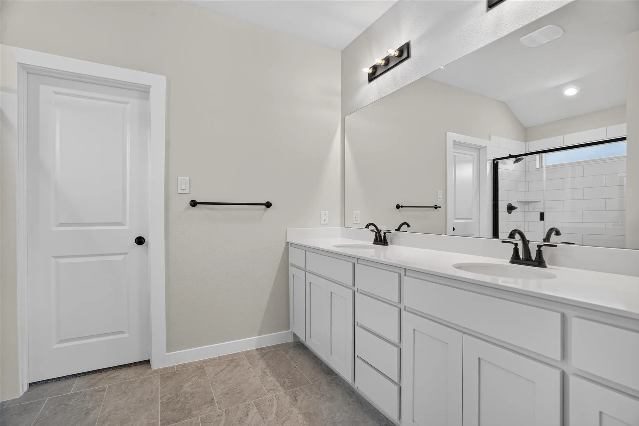Dual vanity with white cabinetry, matte black fixtures, and light countertops