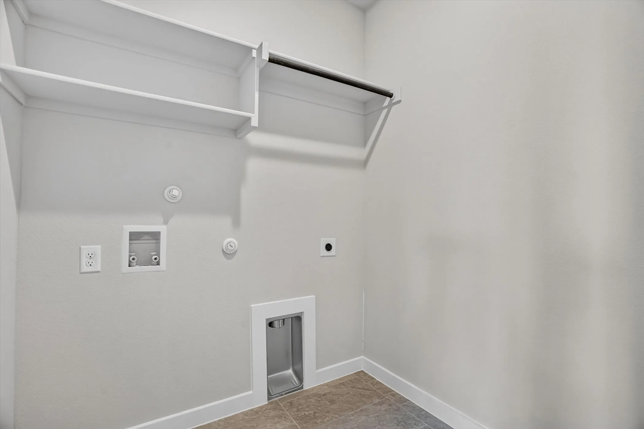 Utility space featuring wall-mounted shelving, a hanging rod, appliance hookups, and tiled flooring