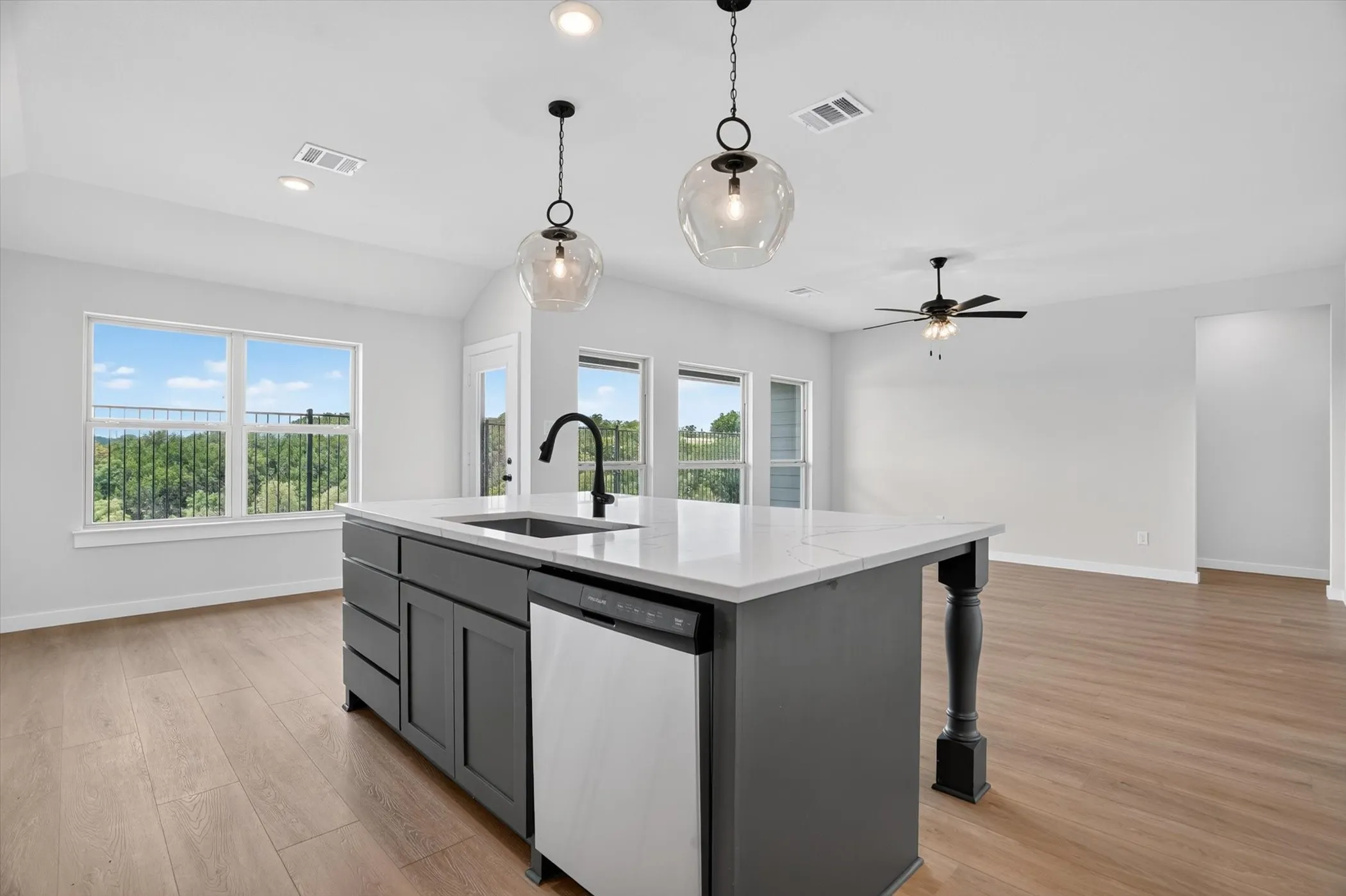 Kitchen island with dark cabinetry, white countertop, and integrated sink with a black gooseneck faucet