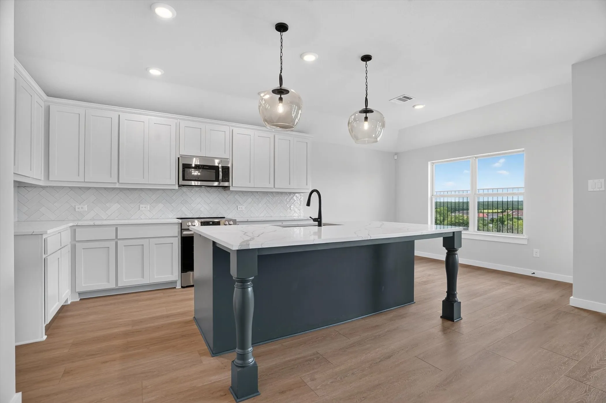 Kitchen featuring white cabinetry, a marble-look countertop island with pendant lighting, a herringbone tile backsplash, stainless steel appliances, and wood-finish flooring