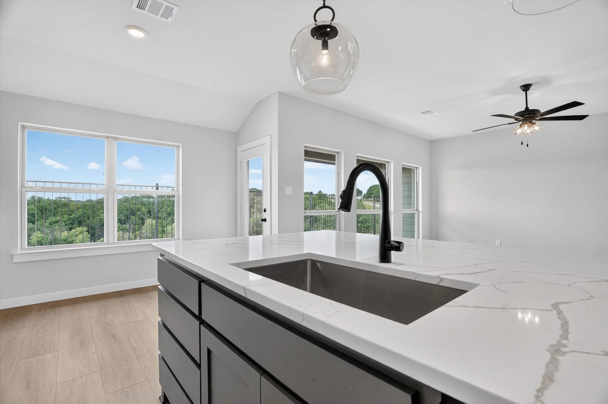 Kitchen island featuring a black undermount sink, gooseneck faucet, and veined countertop