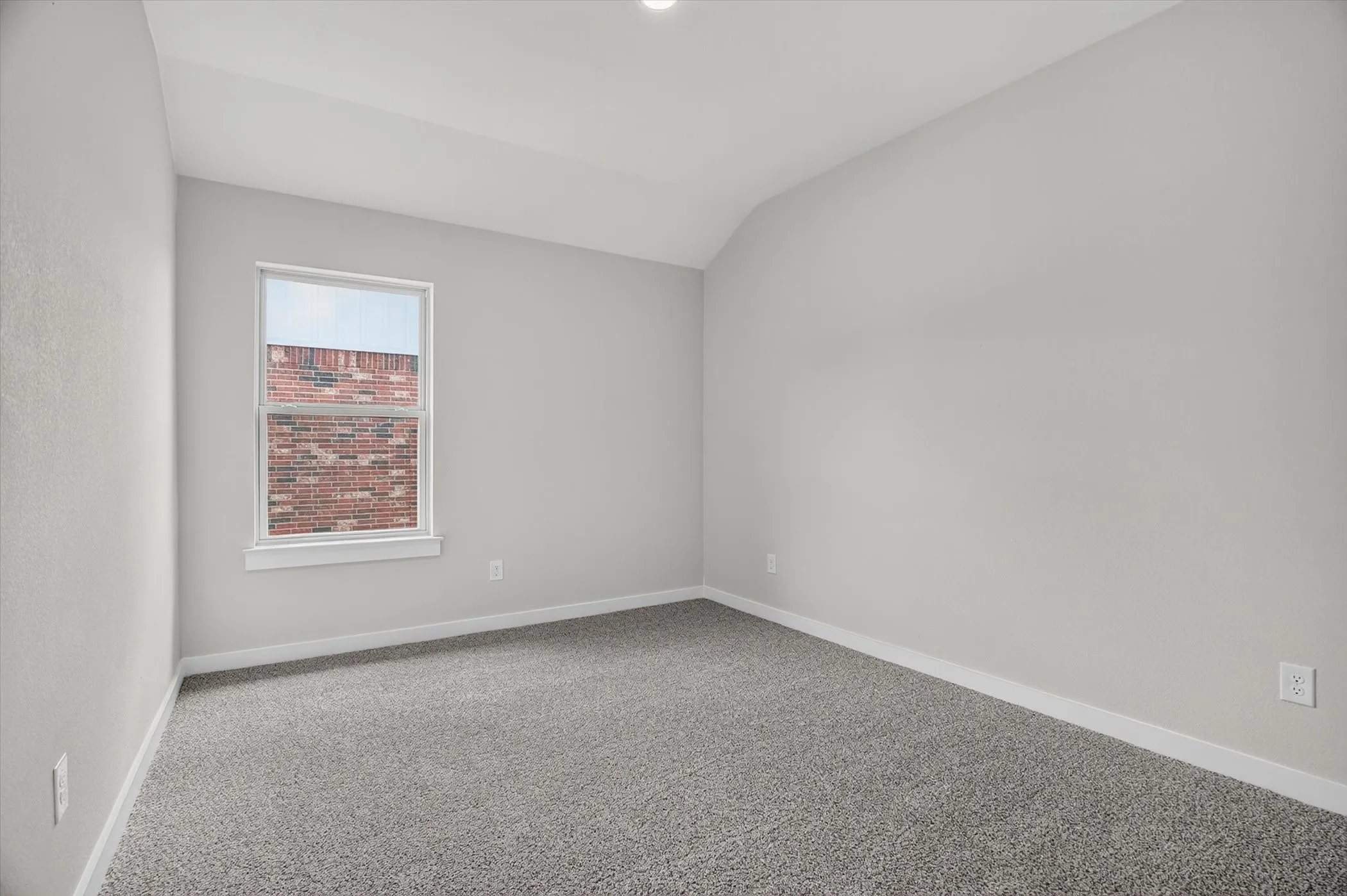 Vaulted ceiling, recessed lighting, neutral wall tones, carpeted flooring, and a double-hung window