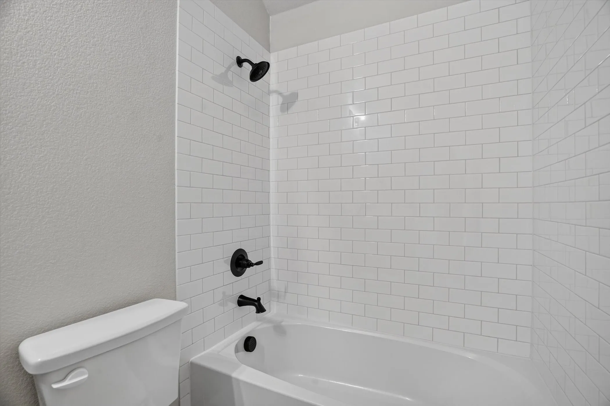 Bathtub with subway tile surround and matte black fixtures