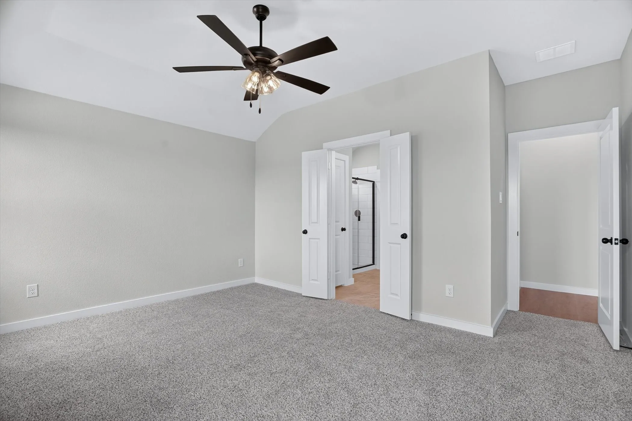 Vaulted ceiling with a contemporary ceiling fan, light gray wall paint, and gray carpeting