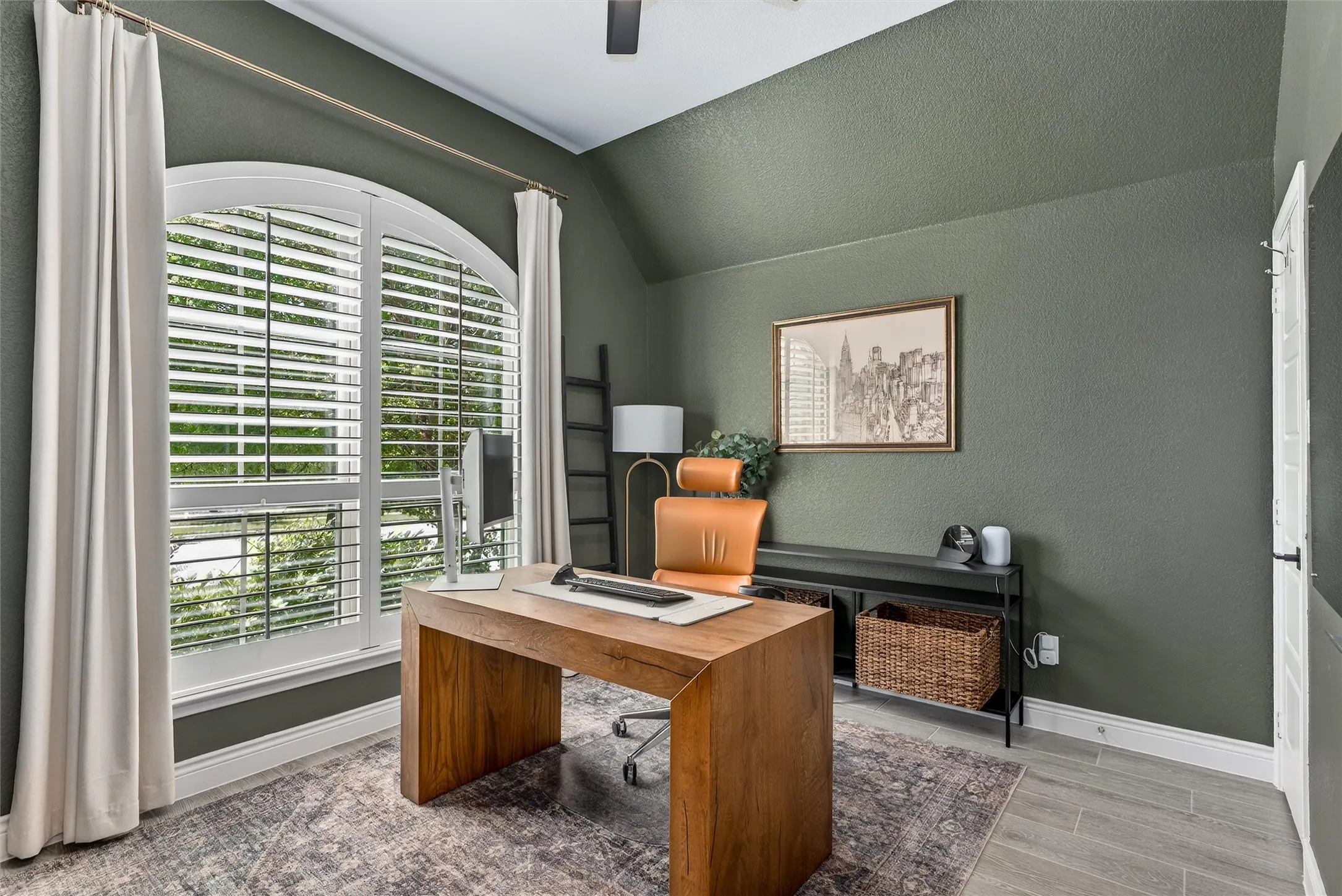 Guest bedroom currently being used as an office with shutters, ceiling fan, and a closet for storage.