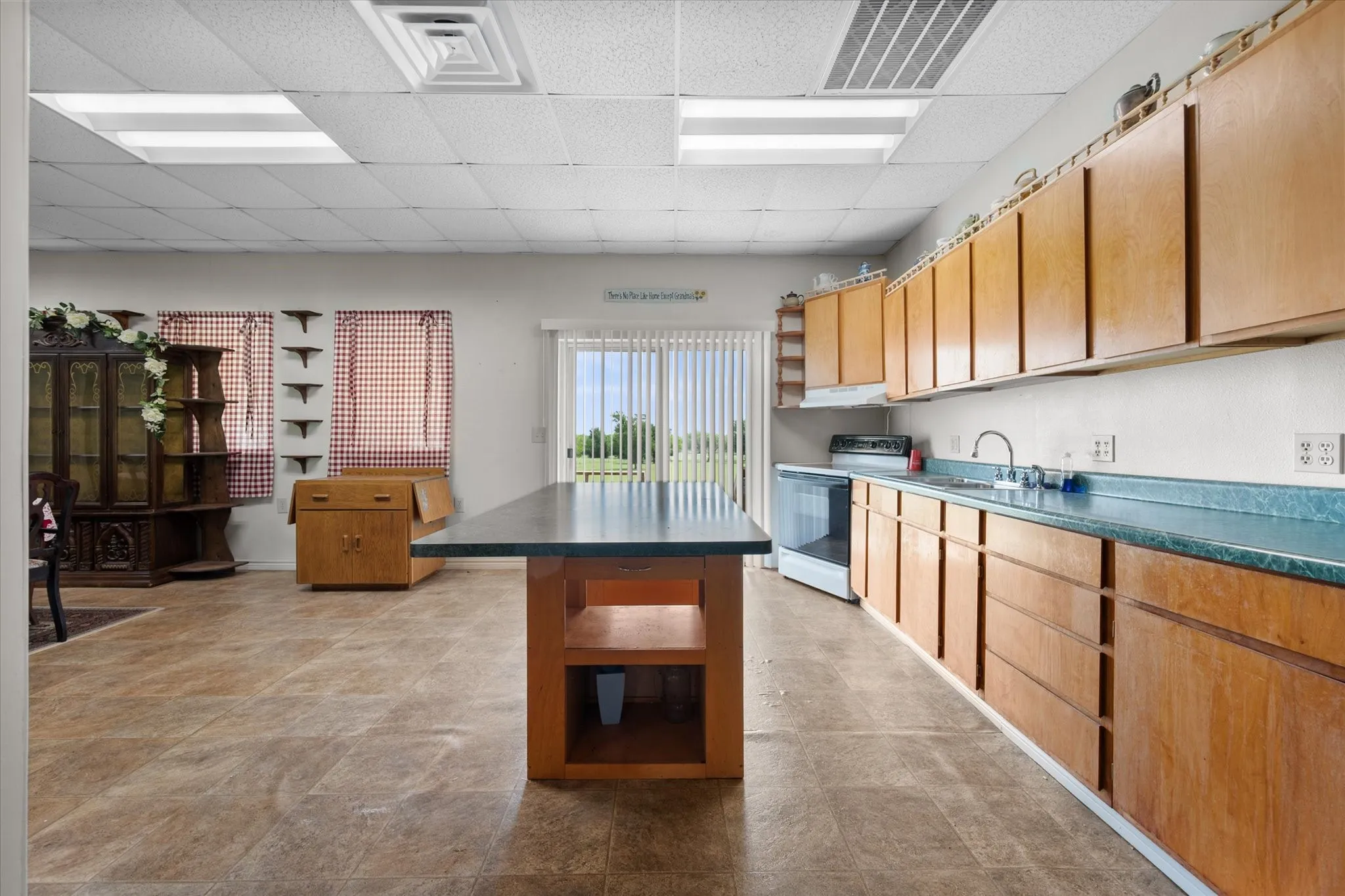 Spacious kitchen featuring extensive wood cabinetry, laminate countertops, a central island, and tile-finish flooring