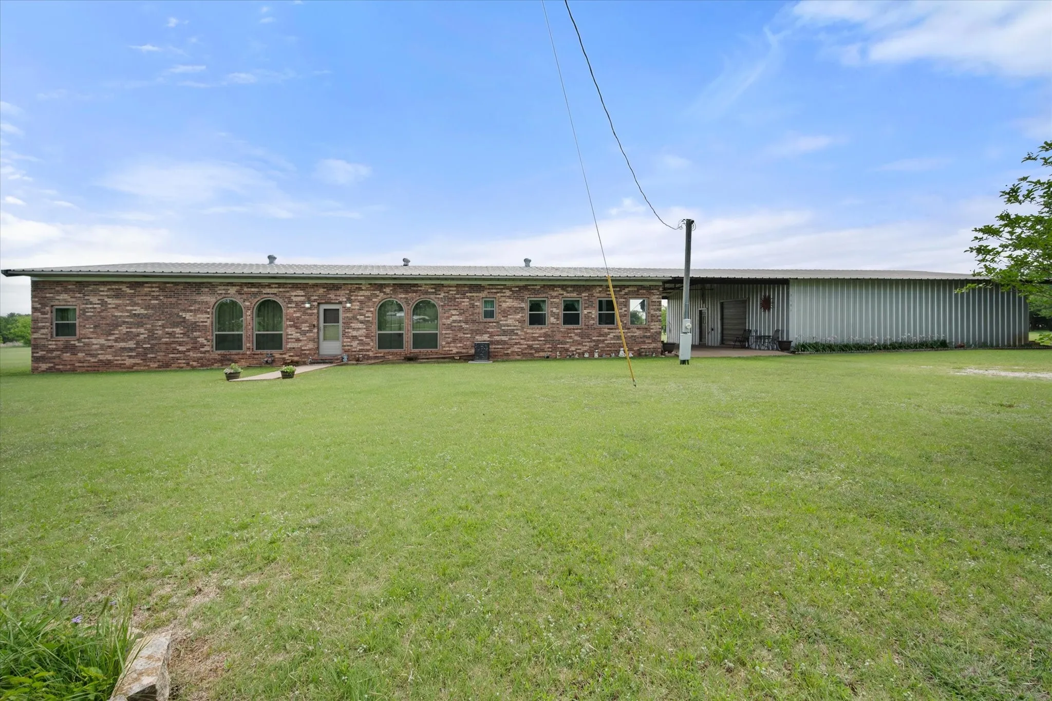 Expansive brick residence with a metal roof and a large, flat lawn