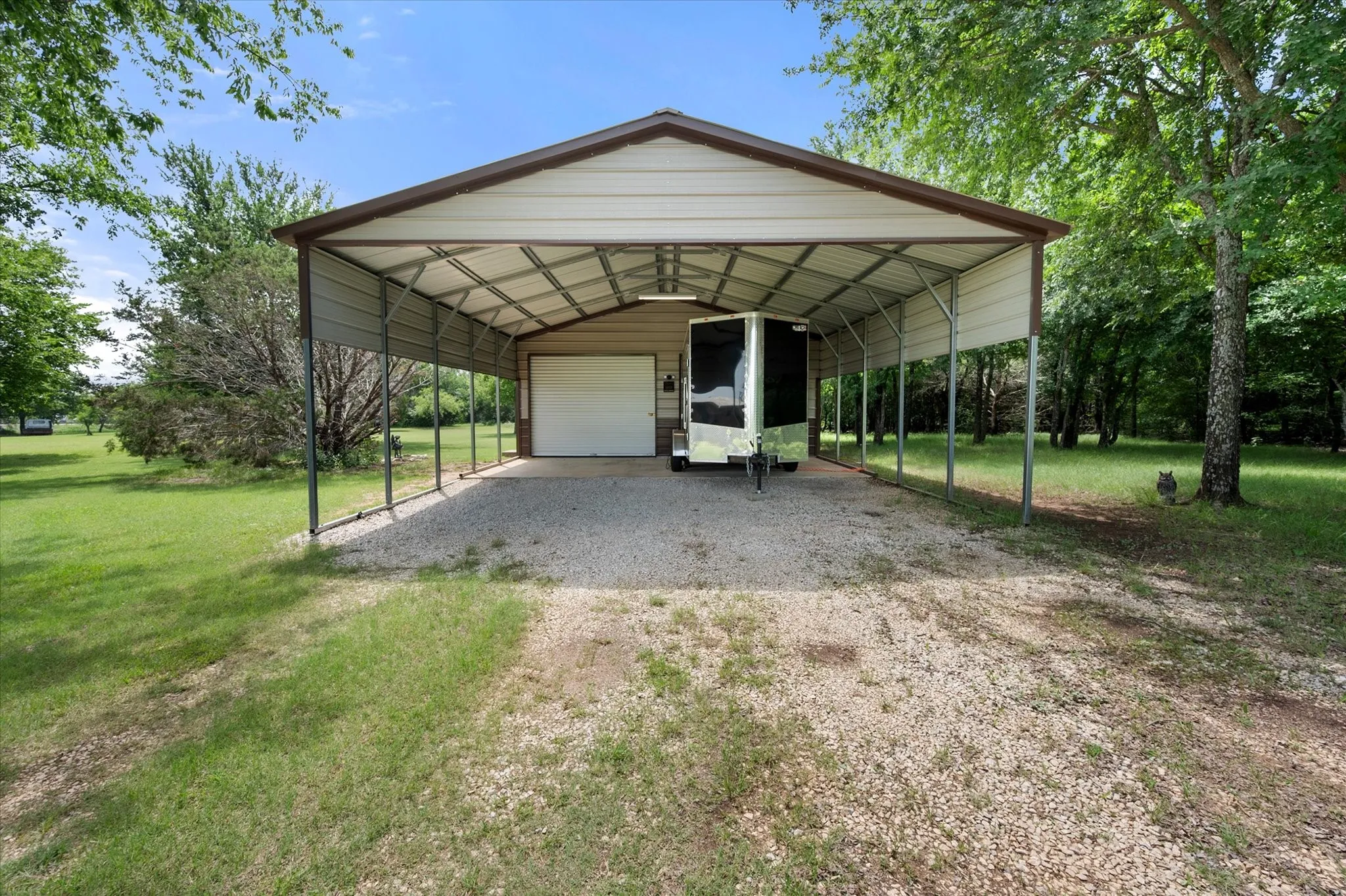 Detached metal carport structure with an integrated single-bay garage