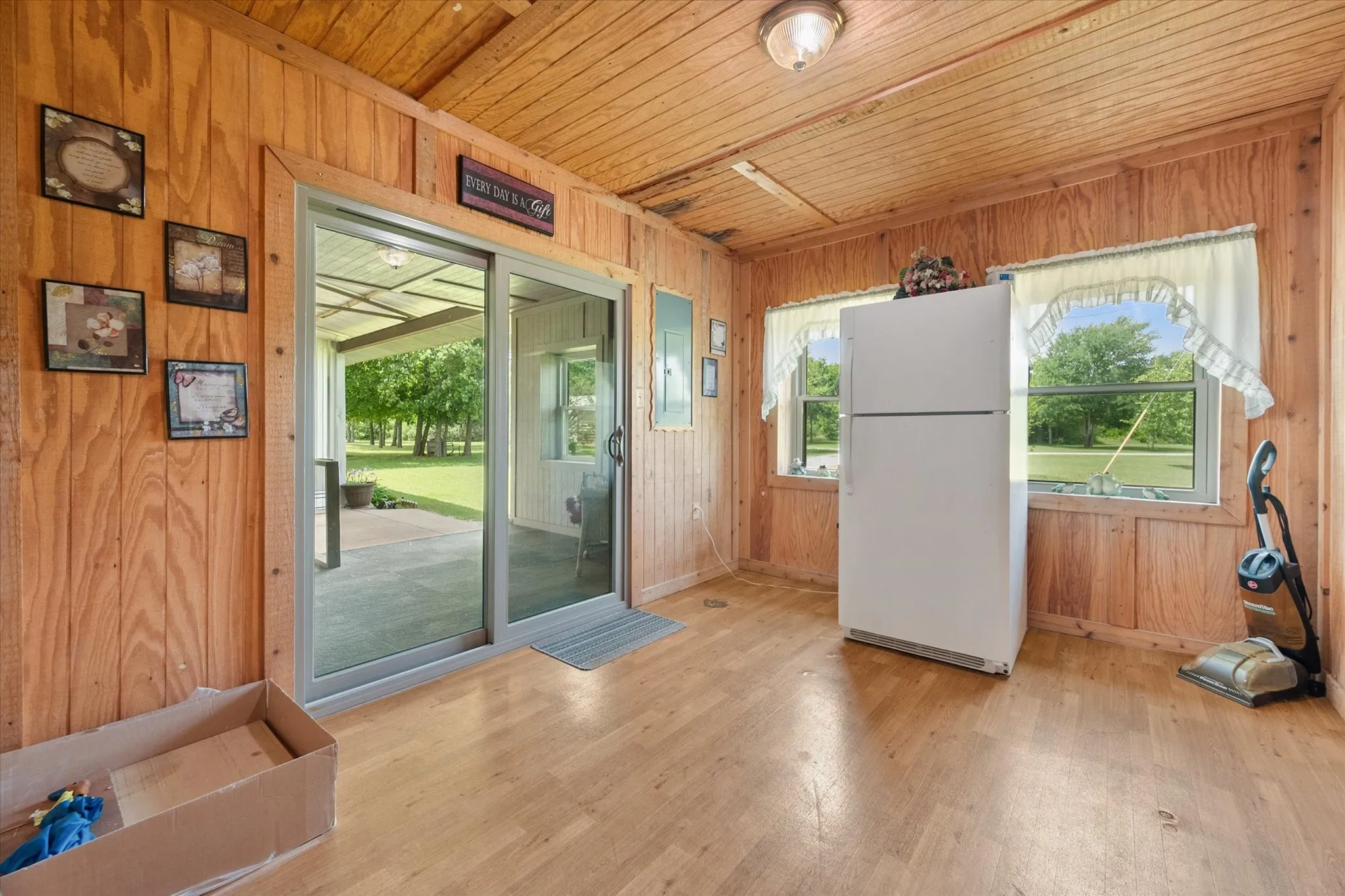 Interior space featuring wood-paneled walls and ceiling, wood-finish flooring, and two windows providing natural light