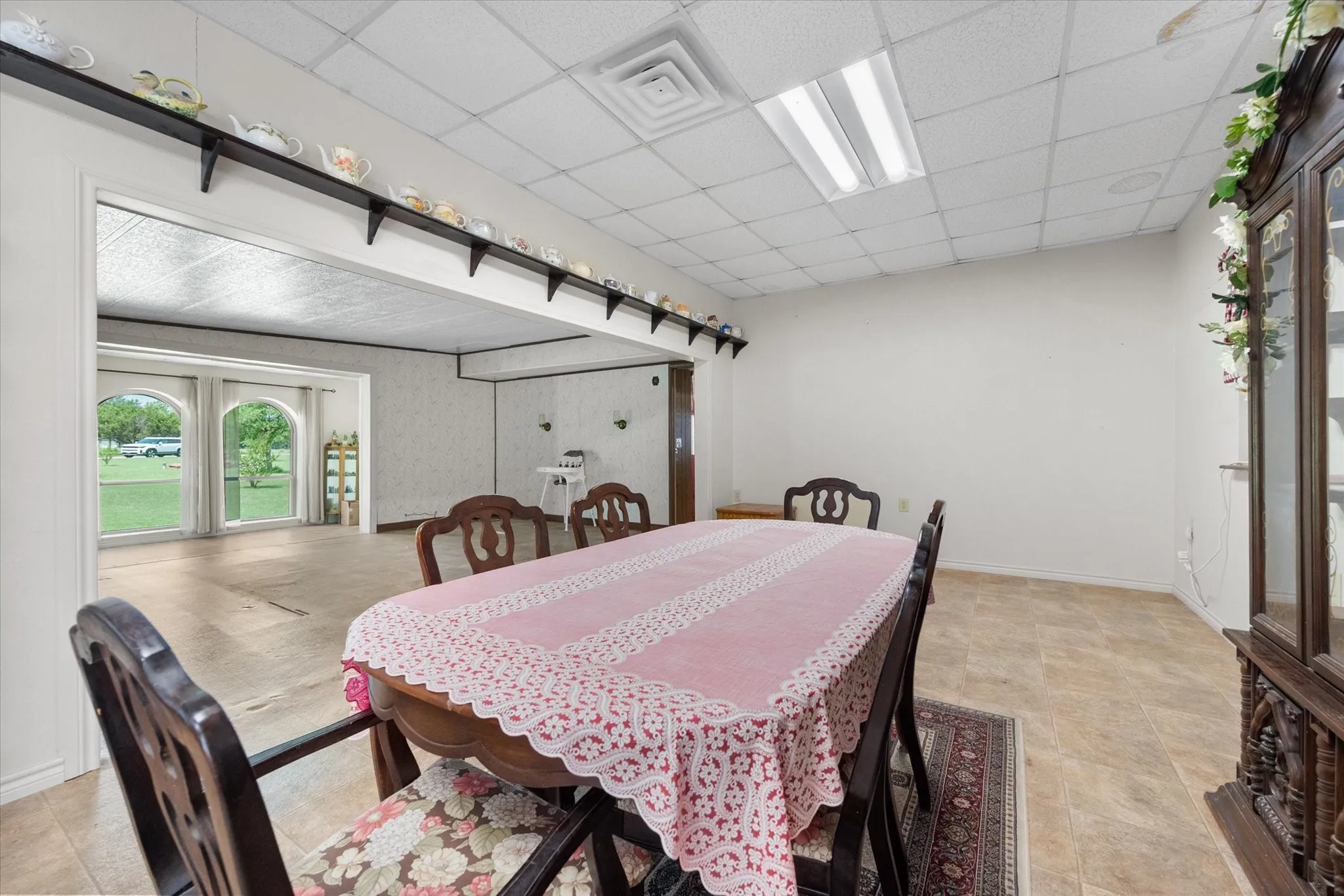 Spacious interior with an open archway leading to an additional area featuring three arched windows