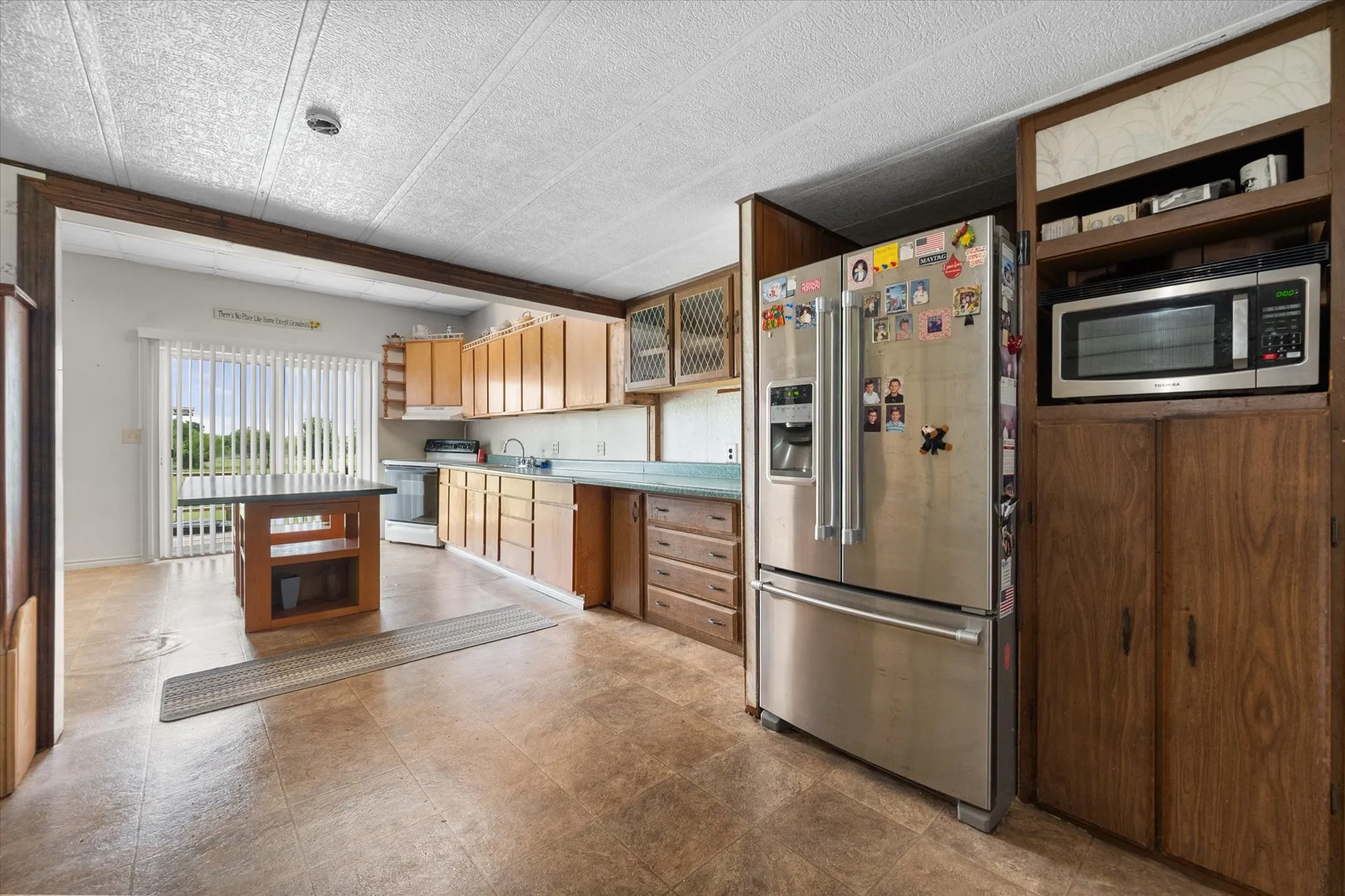 Kitchen featuring wood-finish cabinetry, built-in microwave, stainless steel refrigerator, and central island