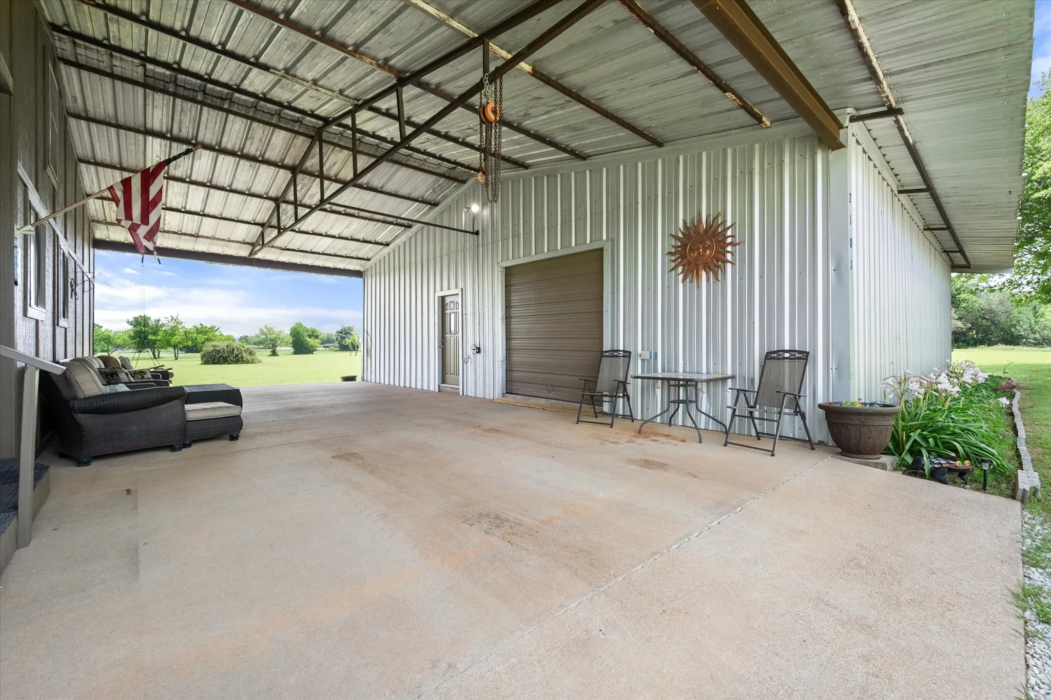 Expansive covered concrete patio featuring a corrugated metal roof and exposed support beams