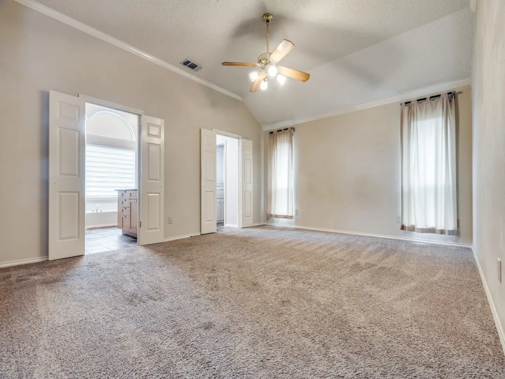 Spare room featuring light carpet, ornamental molding, ceiling fan, a textured ceiling, and vaulted ceiling