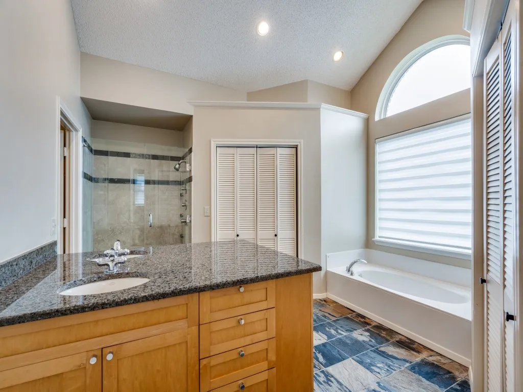 Bathroom with vanity, a textured ceiling, shower with separate bathtub, and lofted ceiling