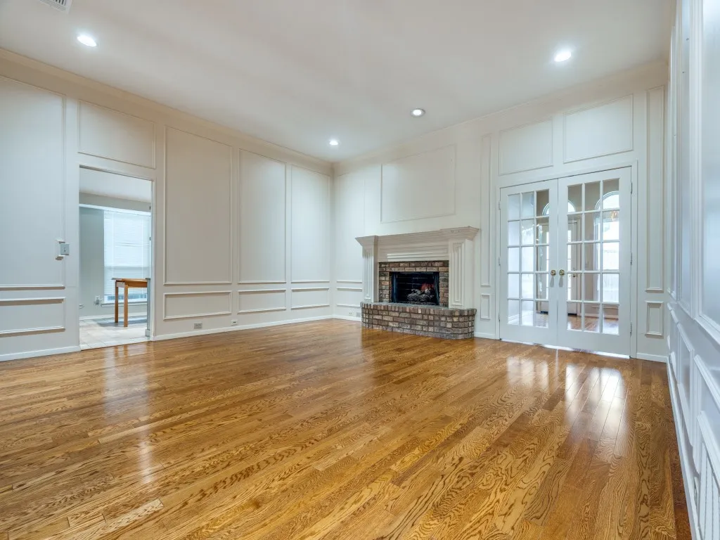 Unfurnished living room featuring crown molding, french doors, a brick fireplace, and light hardwood / wood-style flooring