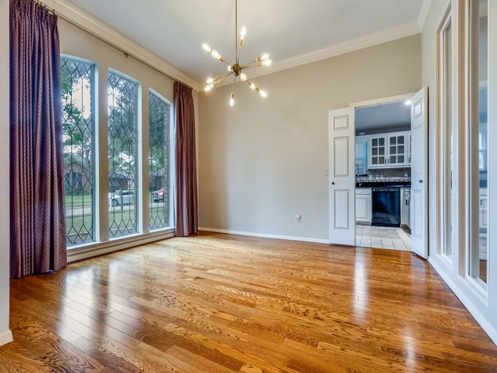 Unfurnished living room featuring an inviting chandelier, light hardwood / wood-style flooring, and ornamental molding