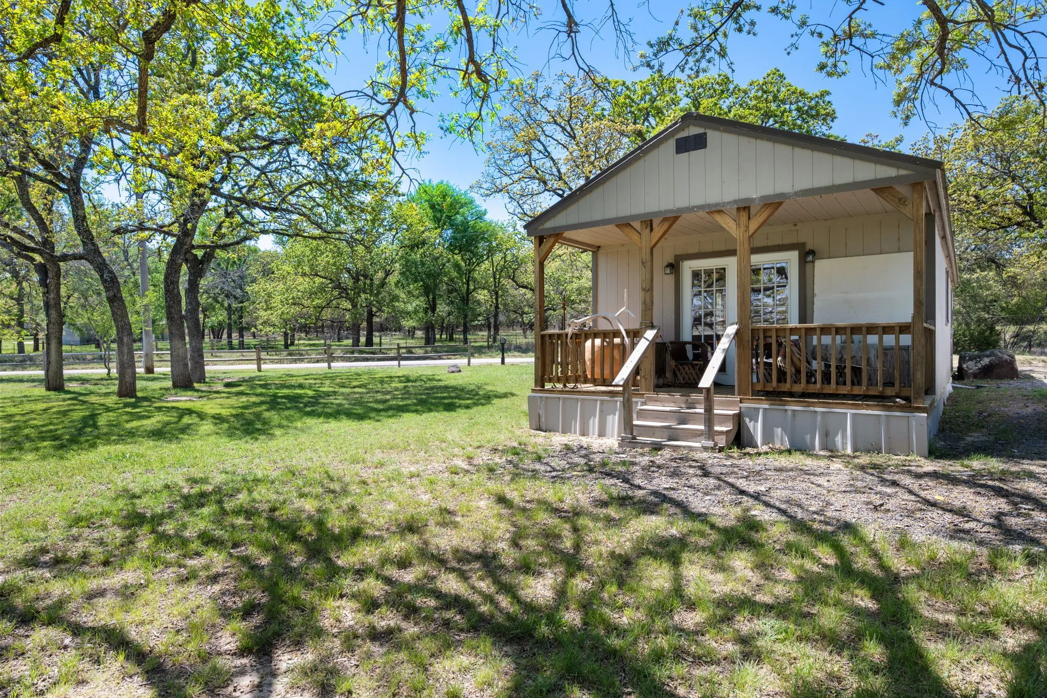 View of front of house featuring a porch, a front lawn, and view of wooded area