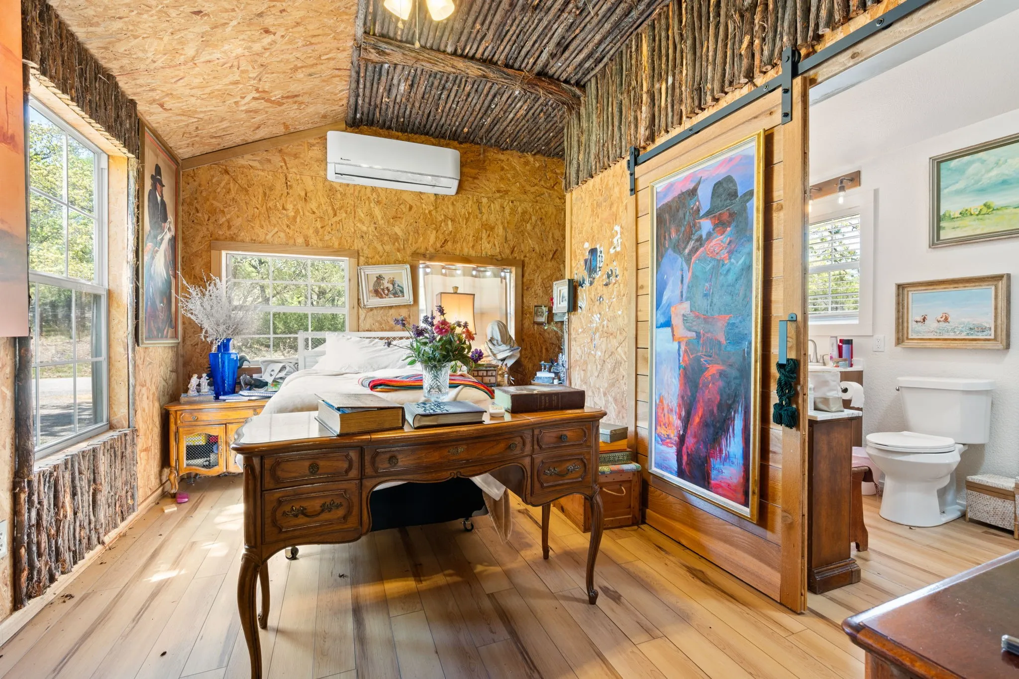 Home office featuring light wood-type flooring, lofted ceiling, and a barn door