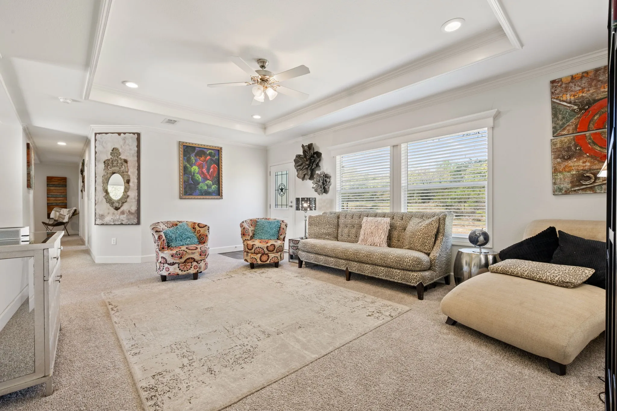Carpeted living area with ceiling fan, crown molding, a raised ceiling, and recessed lighting