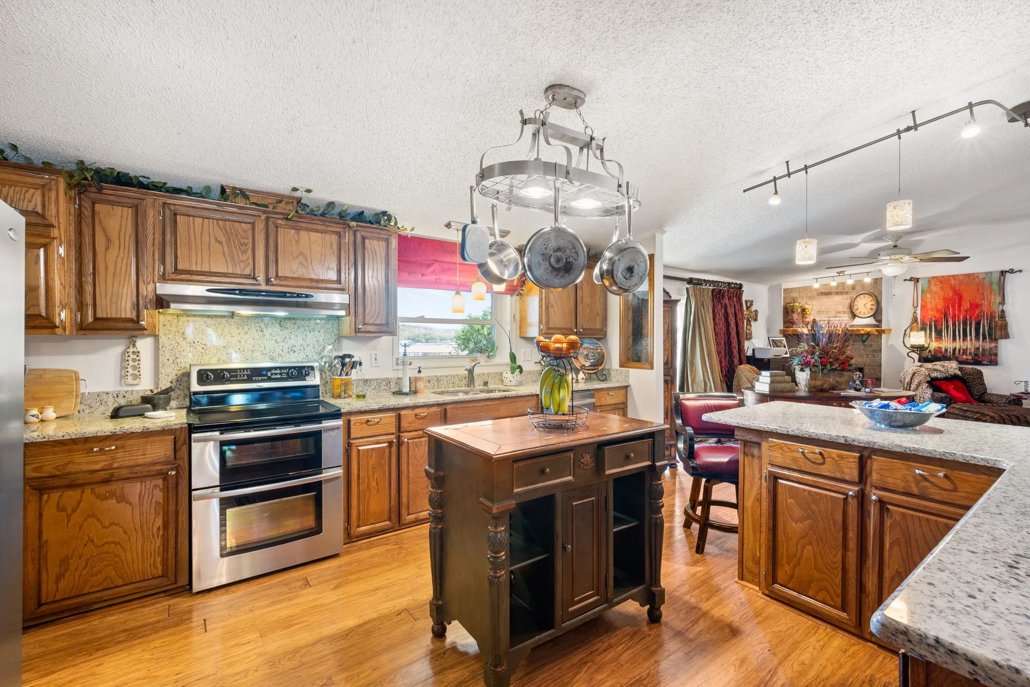 Kitchen with range with two ovens, a textured ceiling, ceiling fan, wood finish cabinetry, and light wood-style floors