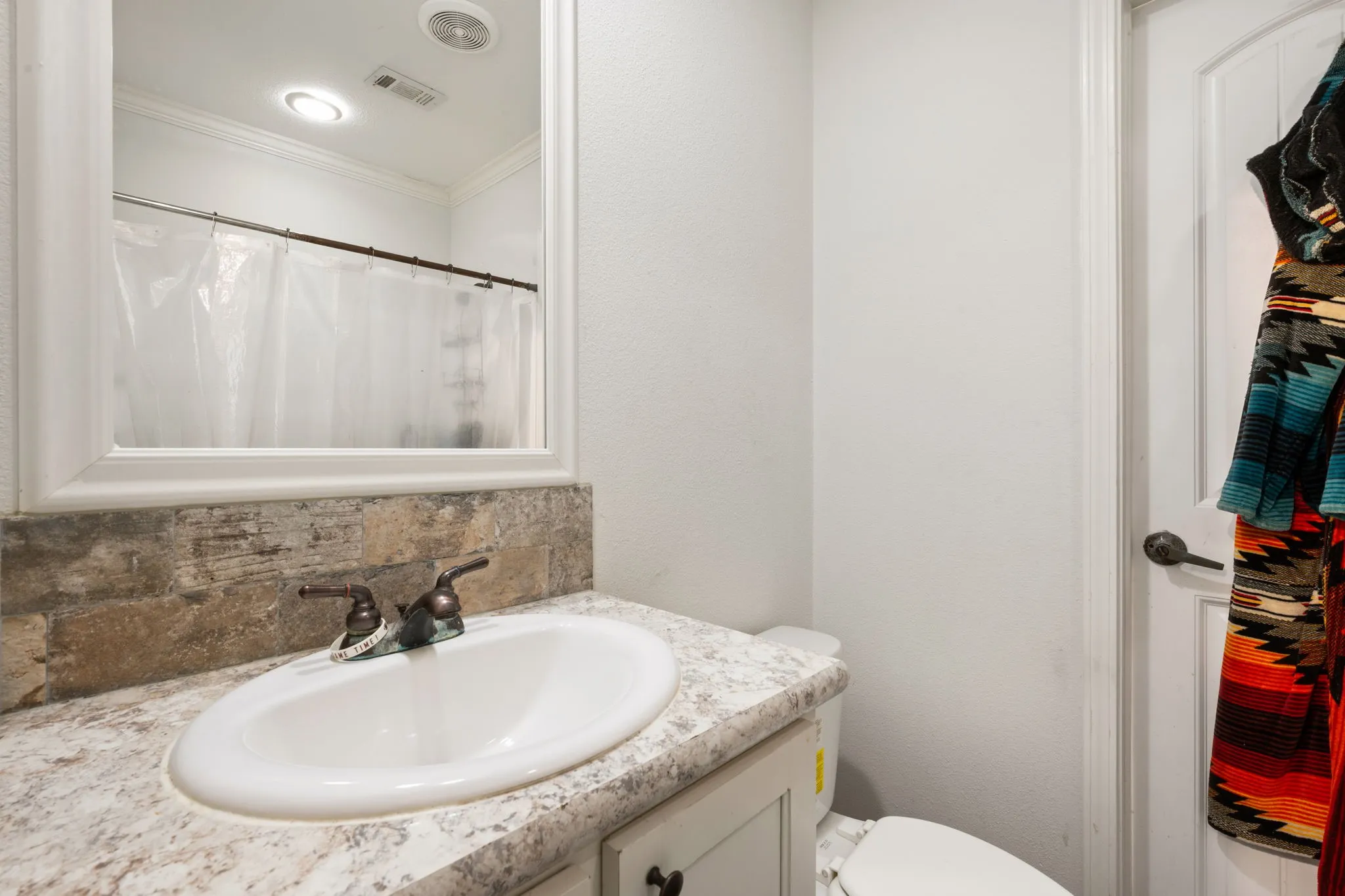 Bathroom with vanity, backsplash, ornamental molding, and curtained shower