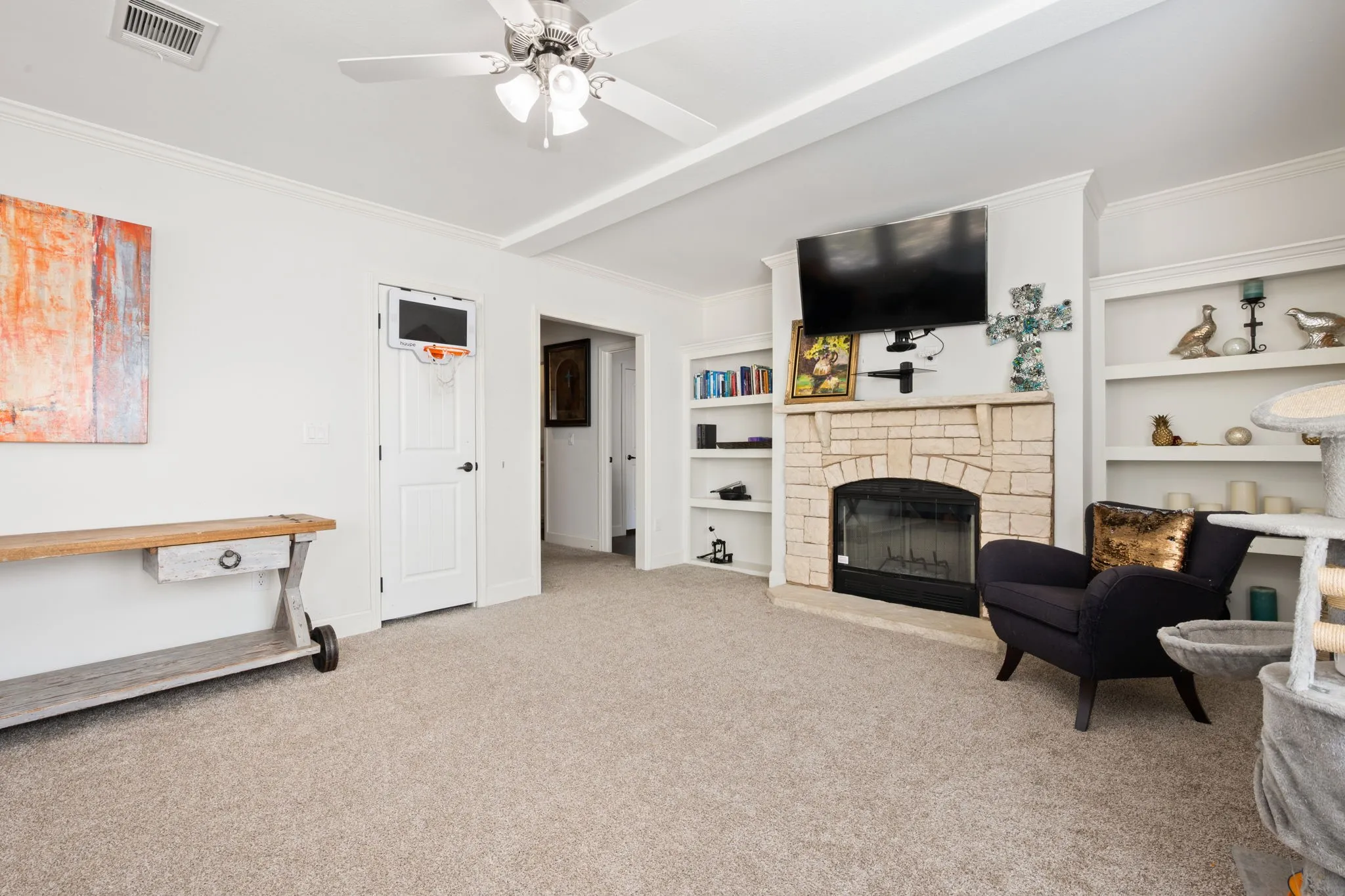 Living area featuring ornamental molding, light colored carpet, a fireplace, ceiling fan, and built in features