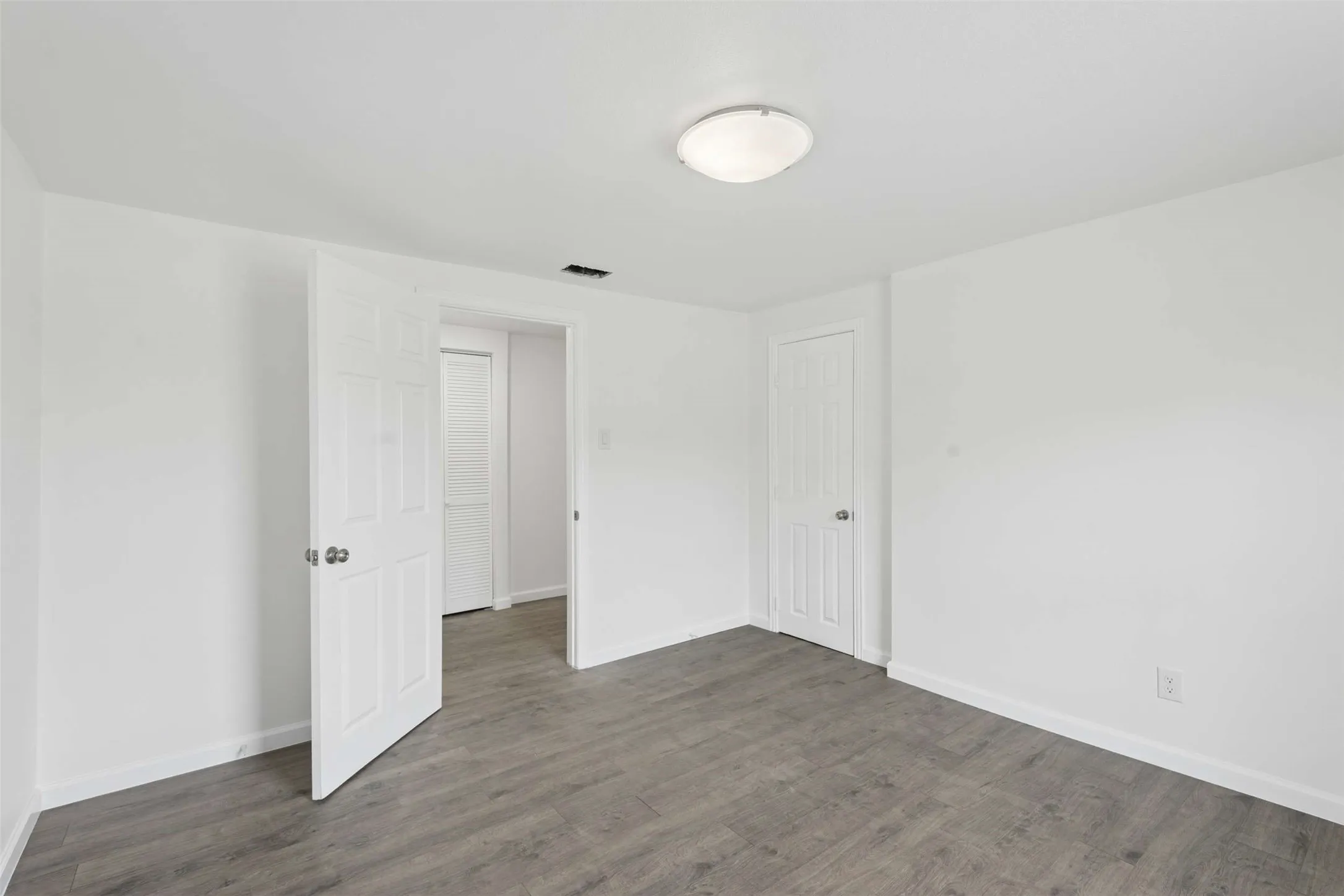 Unfurnished bedroom featuring dark wood-type flooring and baseboards
