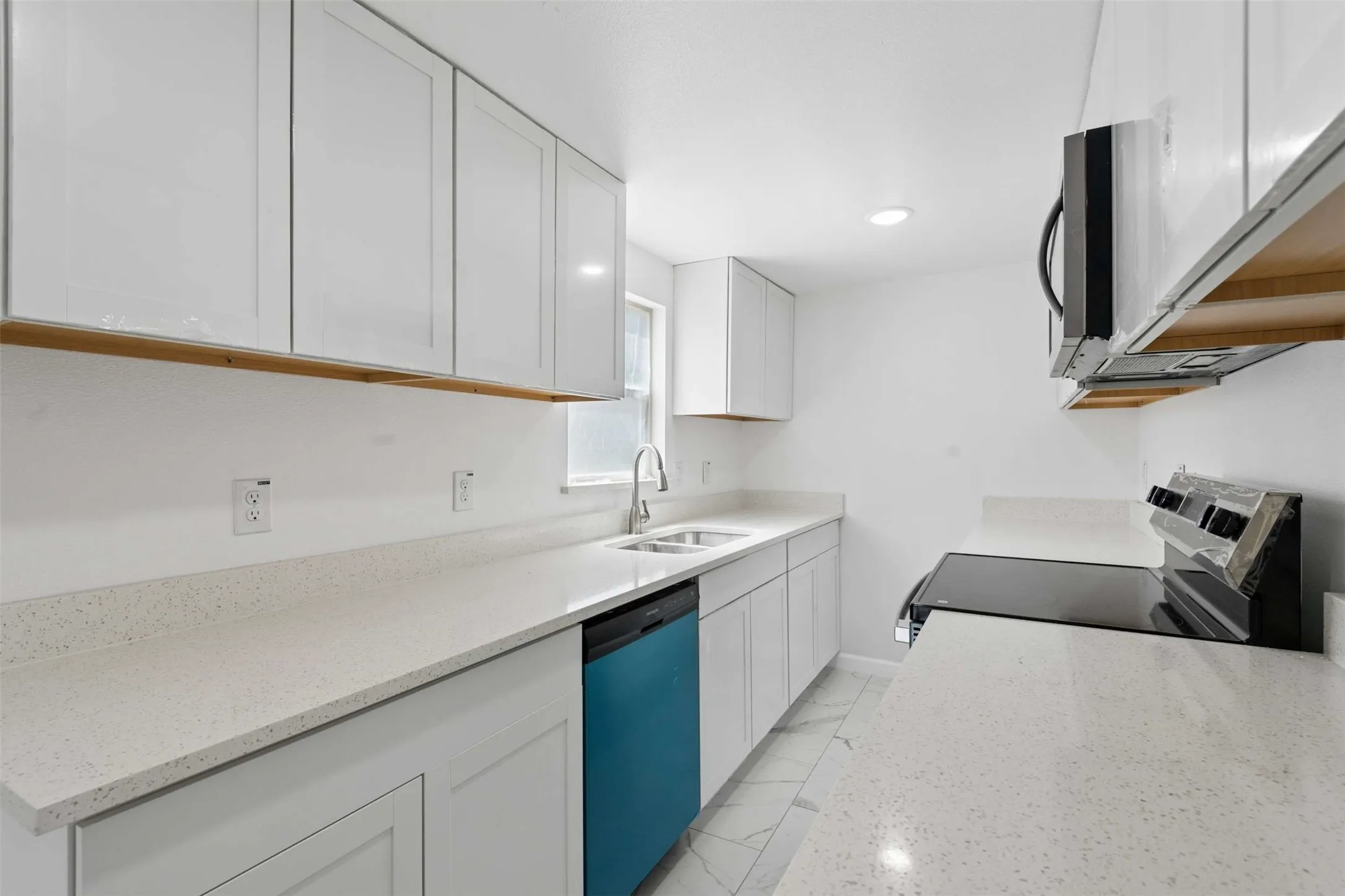 Kitchen with stainless steel appliances, white cabinetry, light stone countertops, and light marble finish flooring