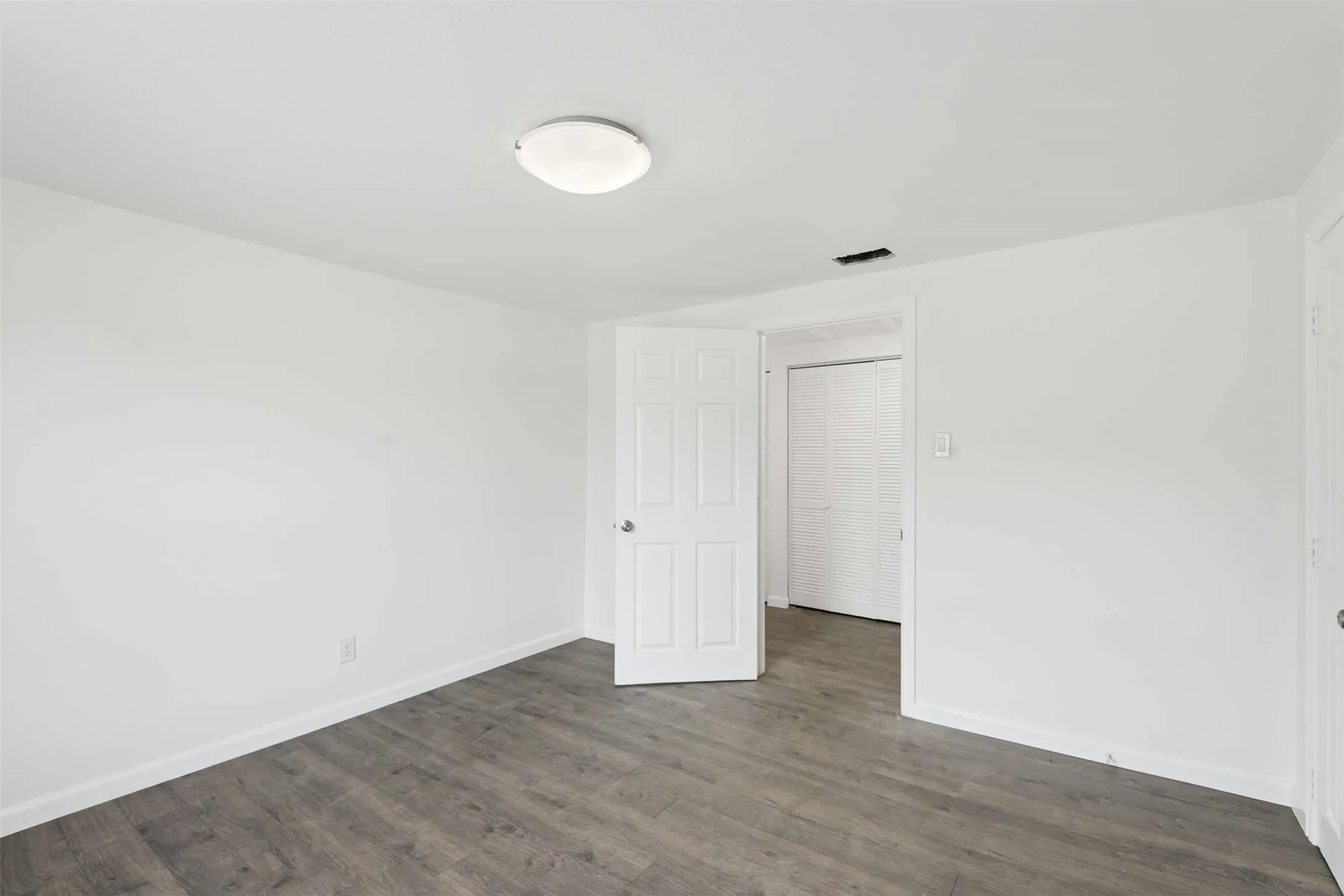 Unfurnished bedroom with dark wood finished floors and baseboards