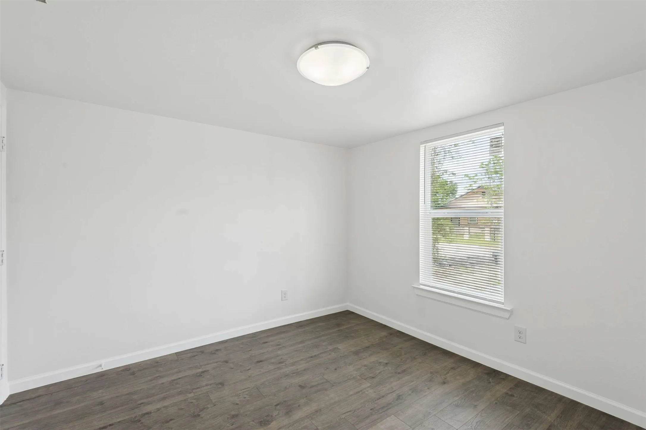 Unfurnished room featuring baseboards and dark wood-style floors