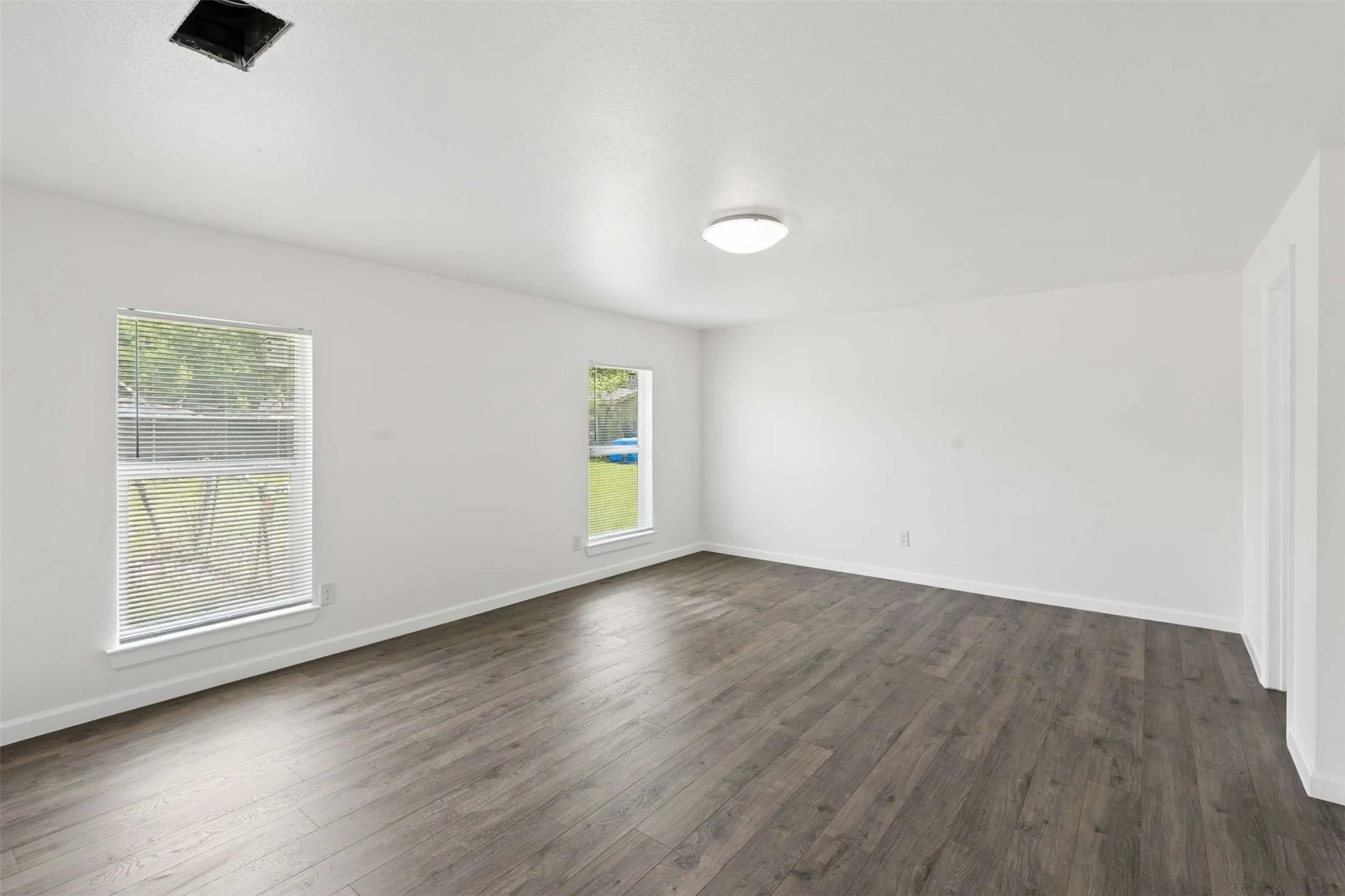 Spare room with baseboards and dark wood-style flooring