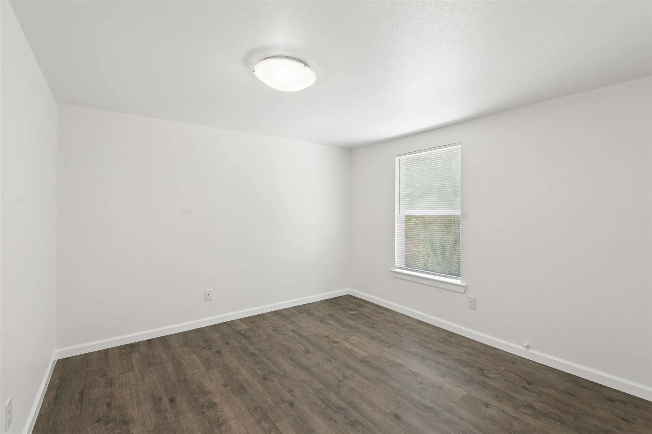 Empty room with dark wood finished floors and baseboards