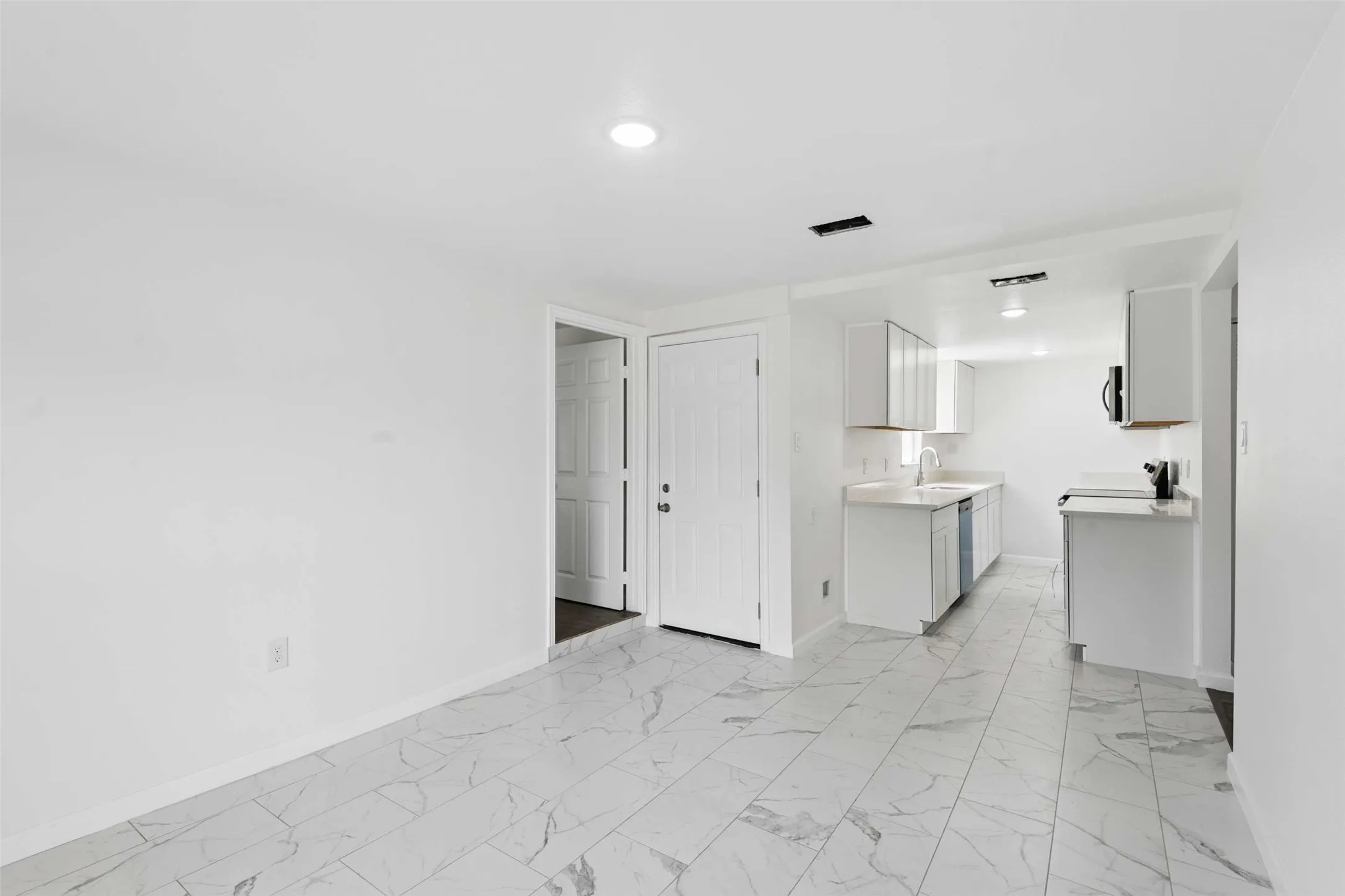 Kitchen featuring light countertops, light marble finish floors, recessed lighting, white cabinets, and stainless steel dishwasher