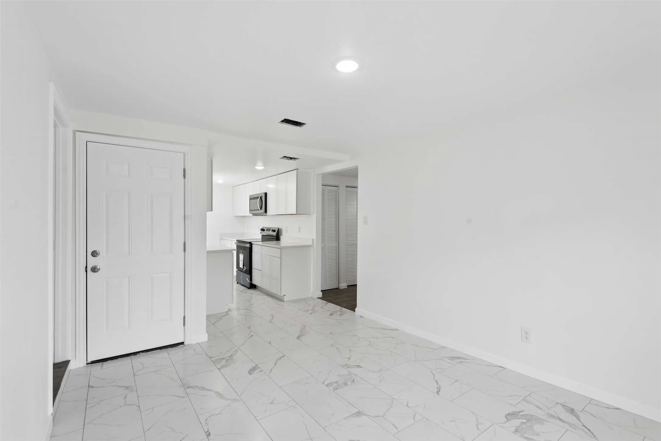 Unfurnished living room with light marble finish floors and baseboards