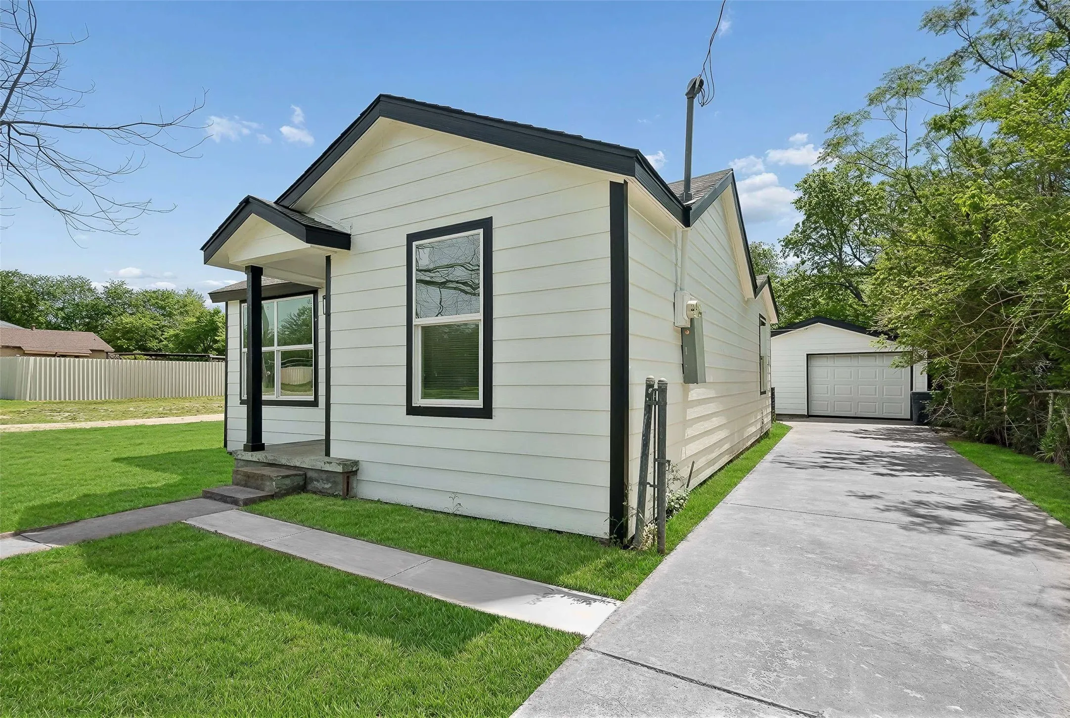 View of side of home featuring a detached garage, an outdoor structure, and concrete driveway