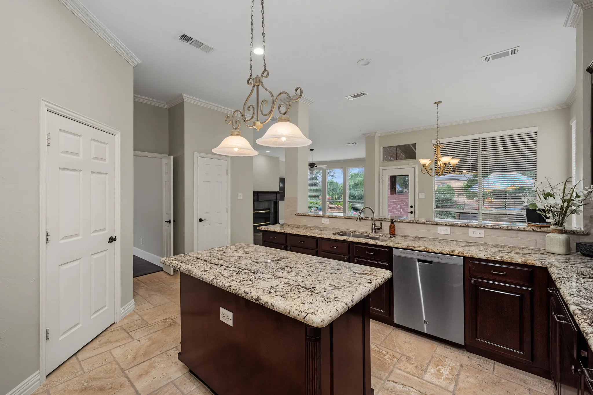 Kitchen featuring a central island with a granite countertop, dark wood cabinetry, tile flooring, and a stainless steel dishwasher