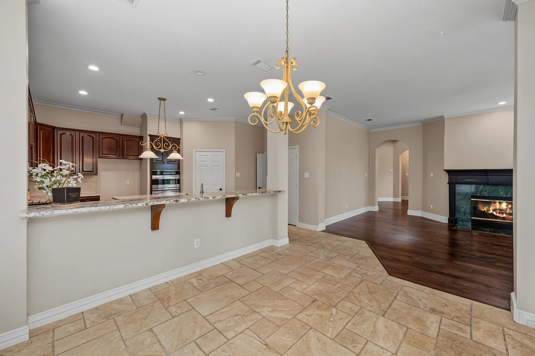 Open-concept area featuring a kitchen pass-through with granite-look countertops and rich wood cabinetry
