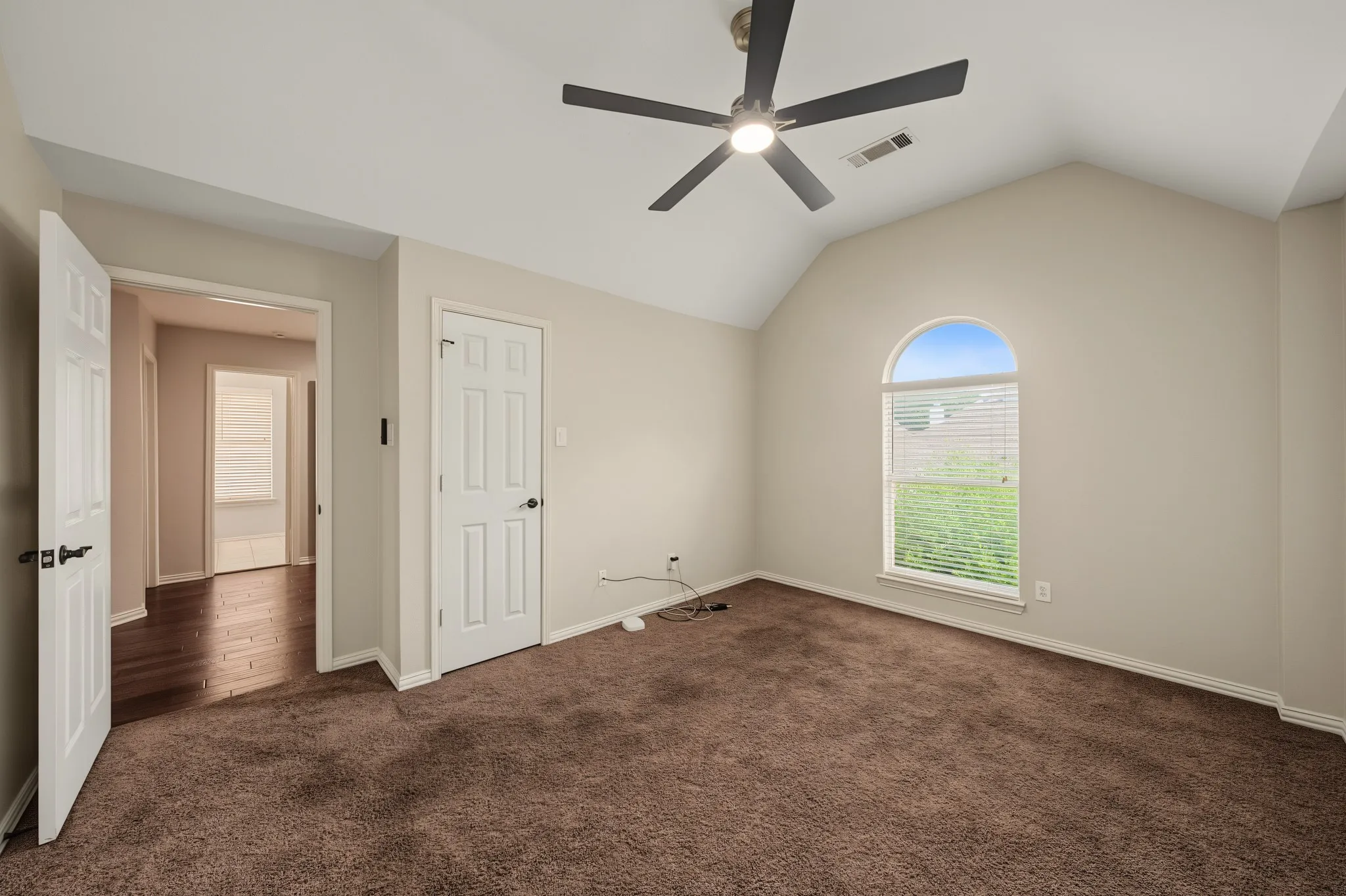 Spacious room featuring vaulted ceilings, a contemporary ceiling fan, and brown carpet flooring